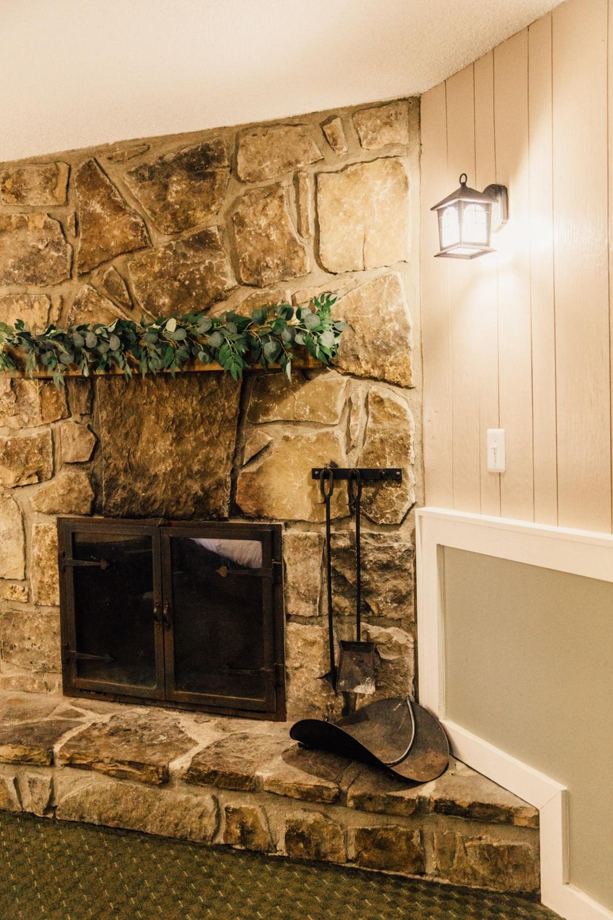 Stone fireplace with eucalyptus garland, fire tools and wall lantern
