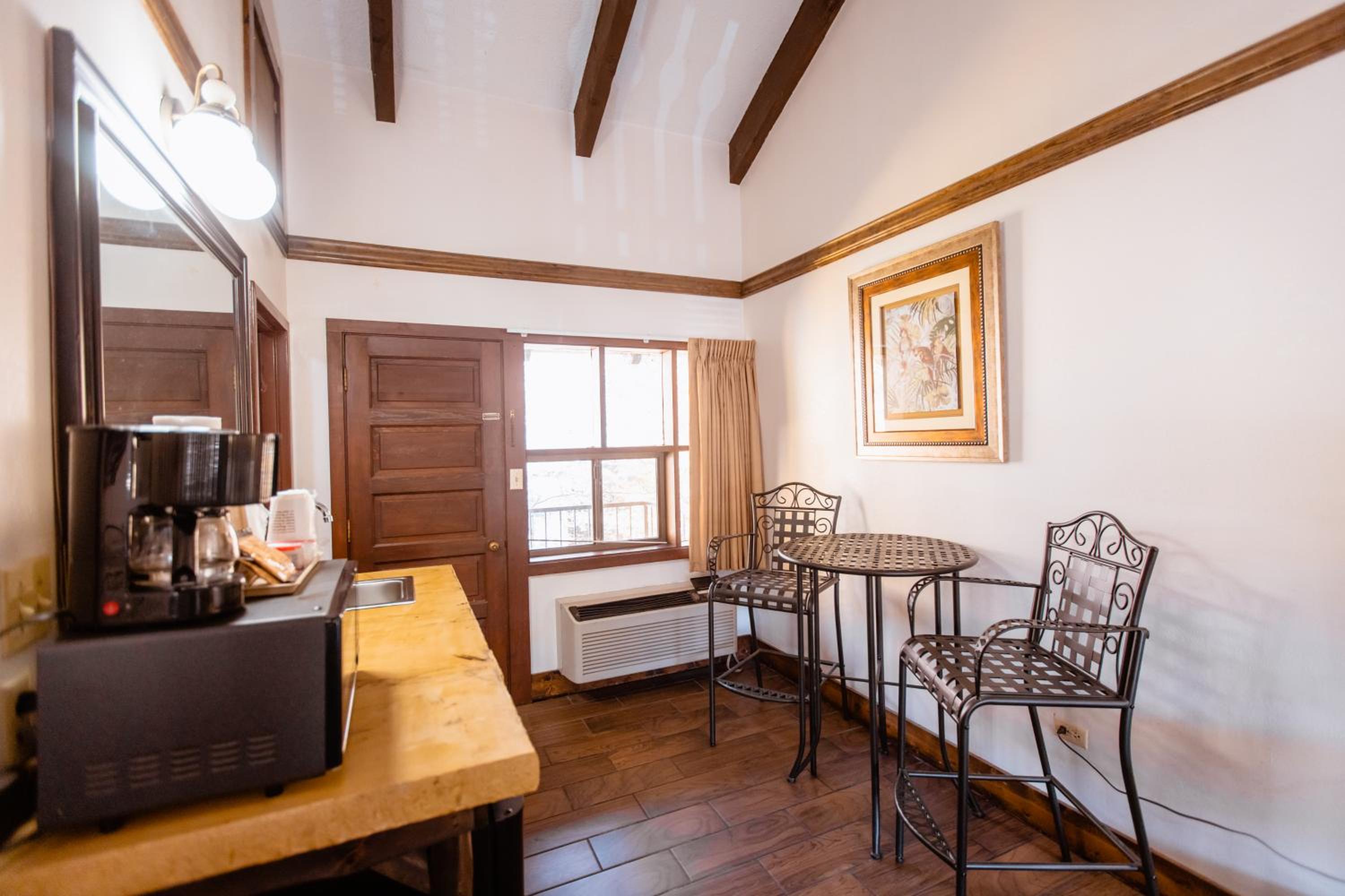 Room corner with coffee station, bistro table and two chairs, beamed ceiling