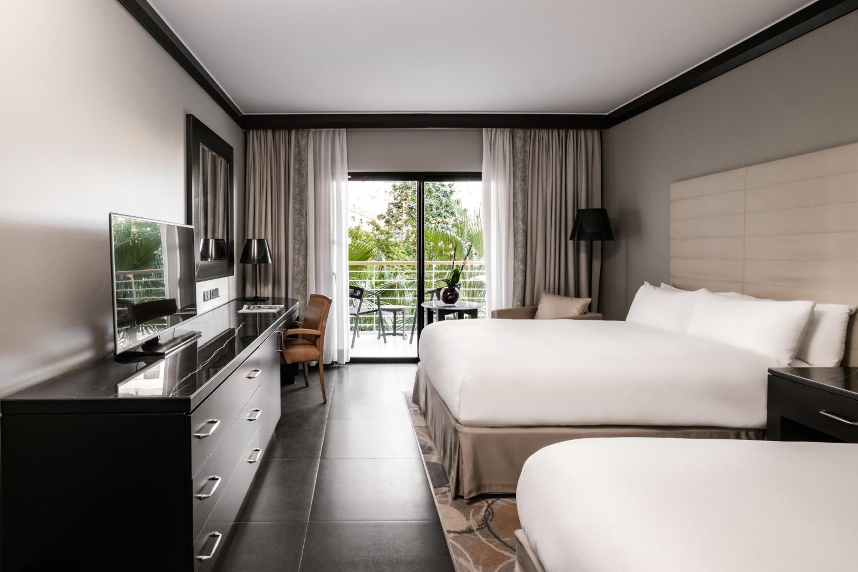 Klassisches Doppelzimmer mit zwei Doppelbetten und Gartenblick
