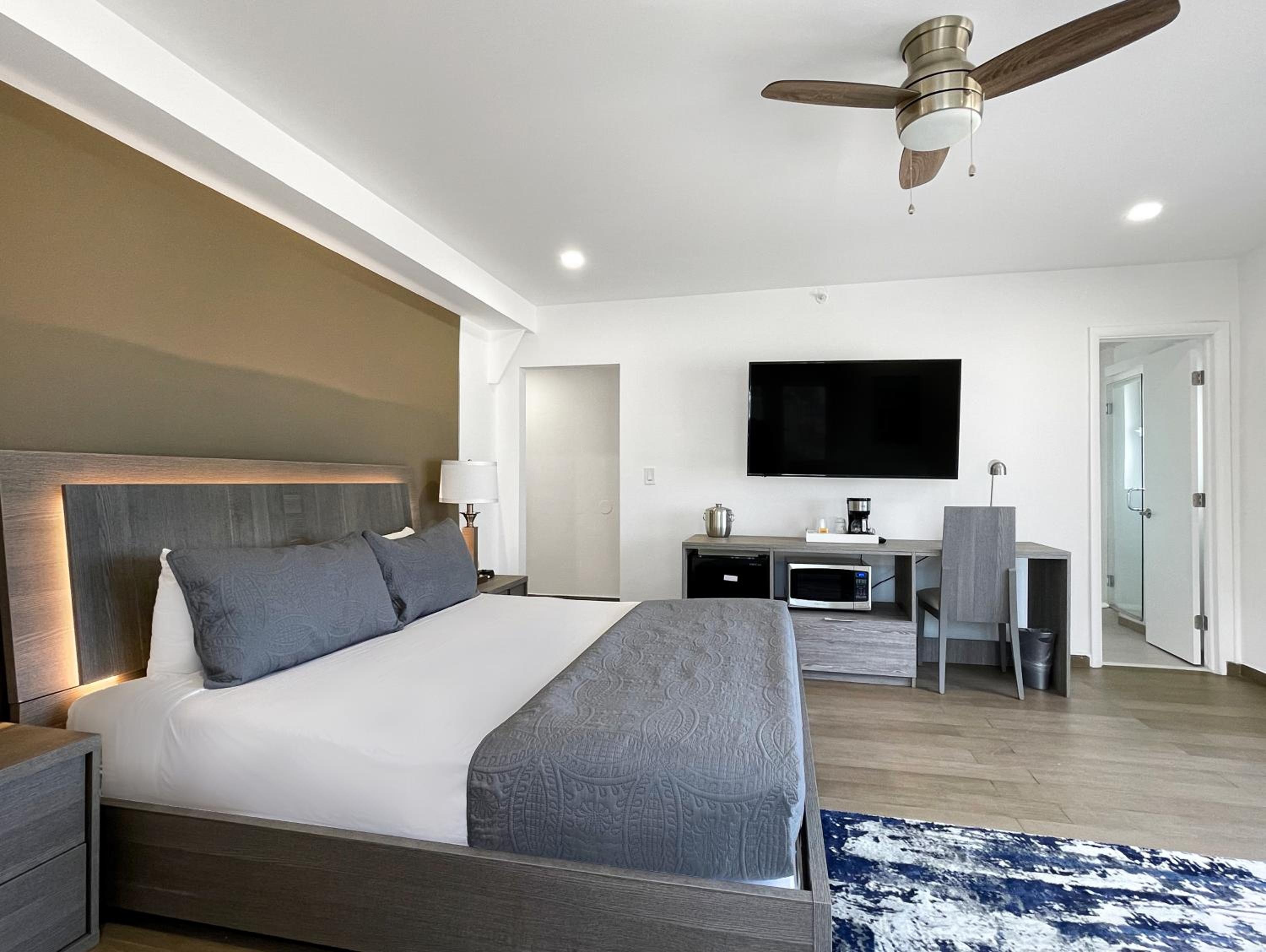 Hotel room with a large bed, gray bedding, and a wall-mounted TV.