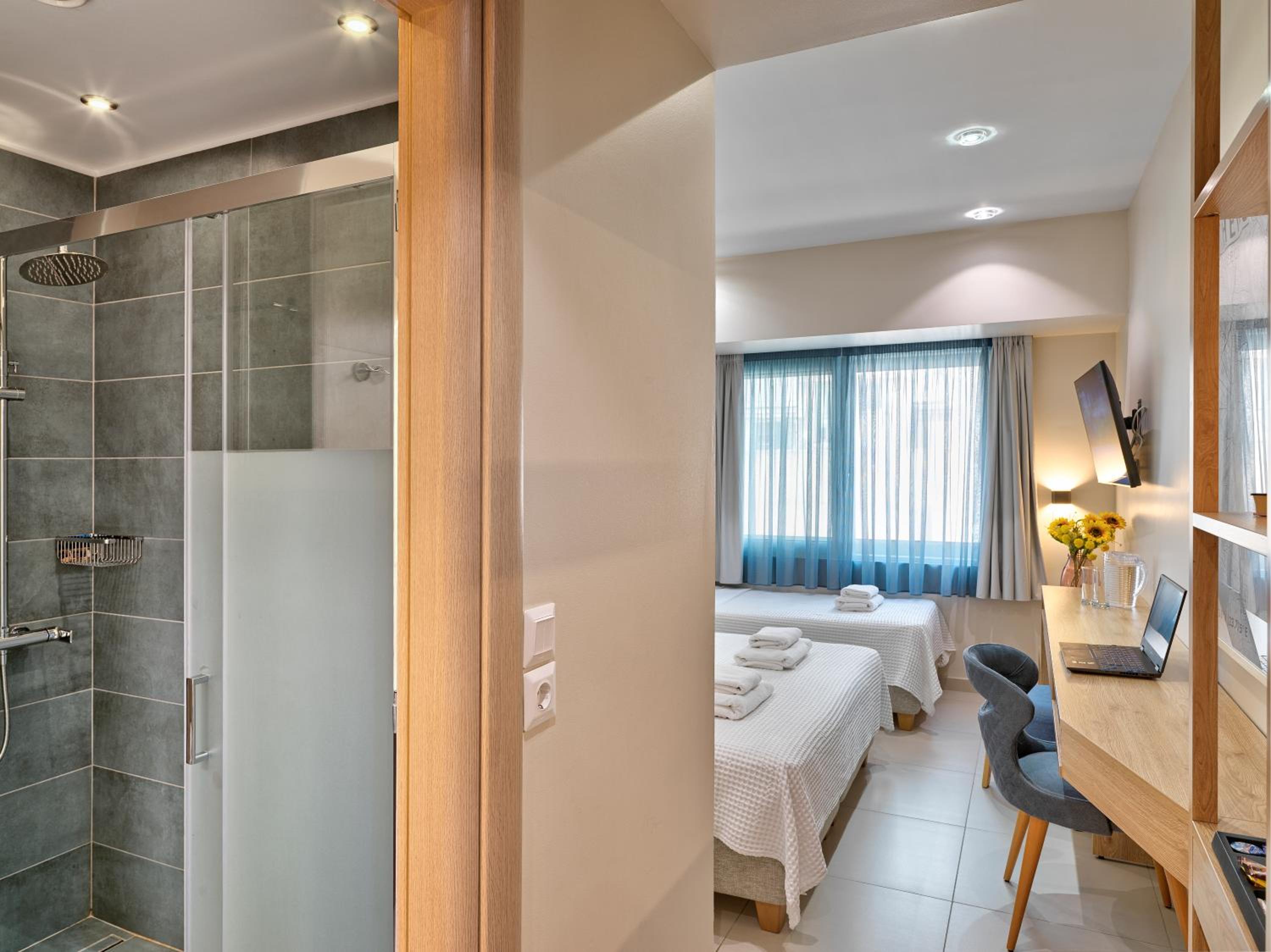Hotel room with two single beds, a desk, and a glass-enclosed shower.