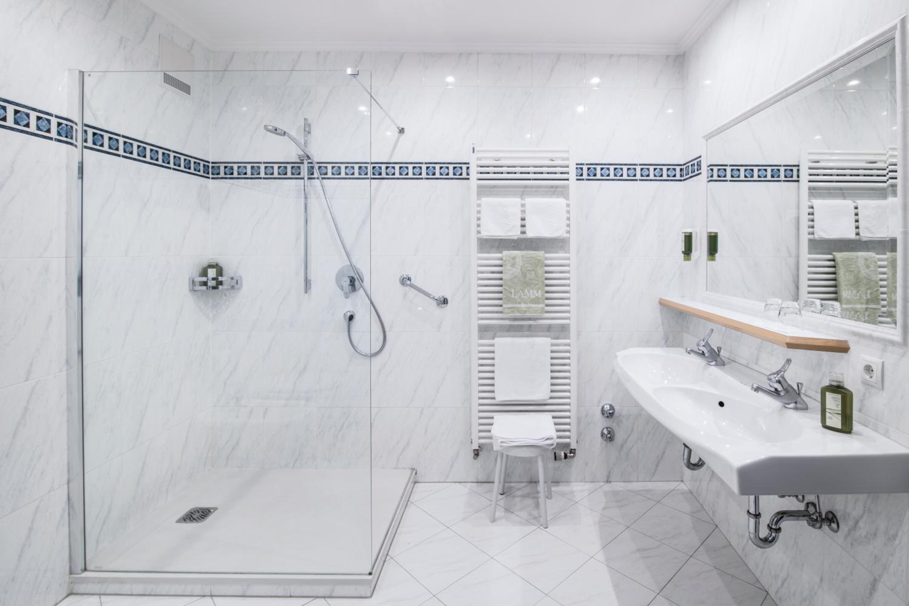 White marble bathroom featuring a glass-enclosed walk-in shower and a double vanity sink.