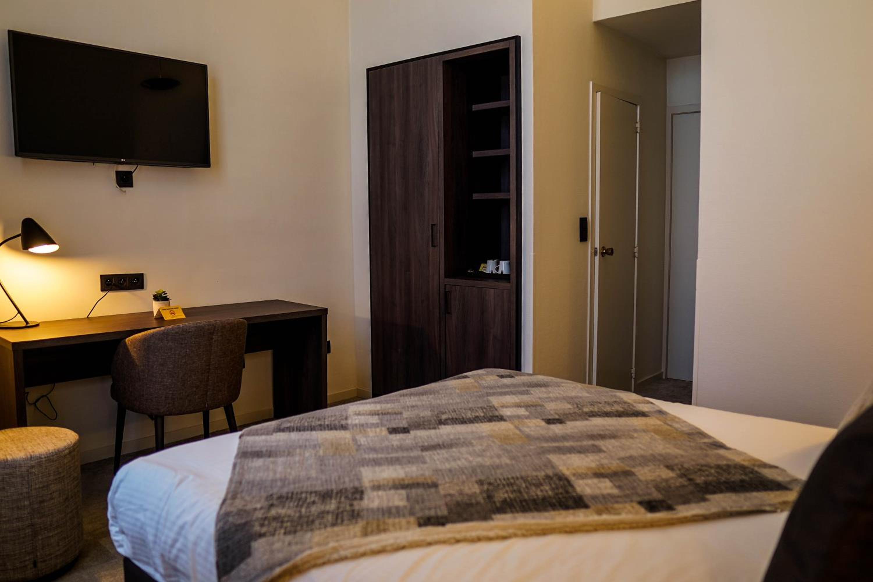 hotel room with a bed, desk, and television