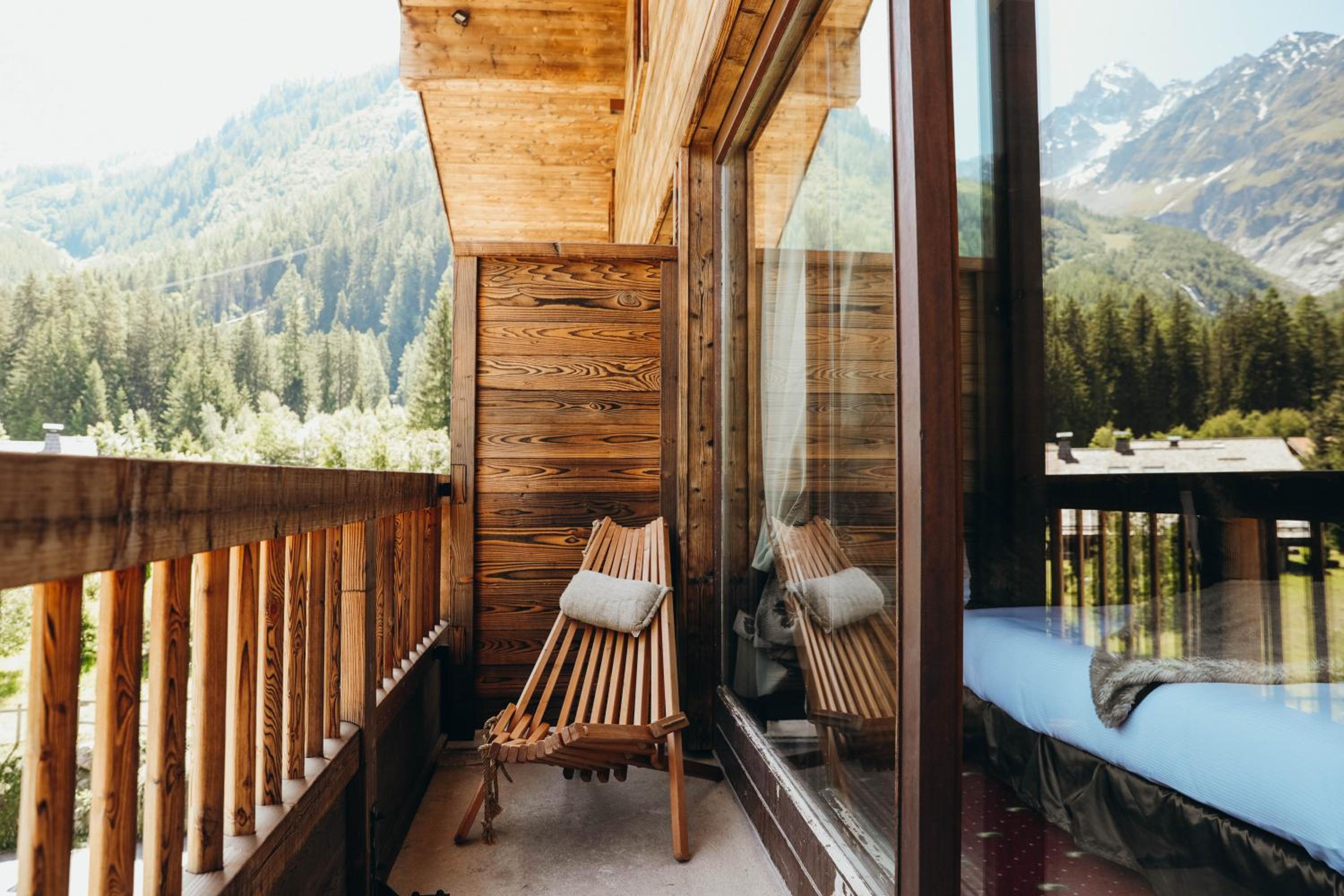Wooden balcony with a slatted chair and mountain view.