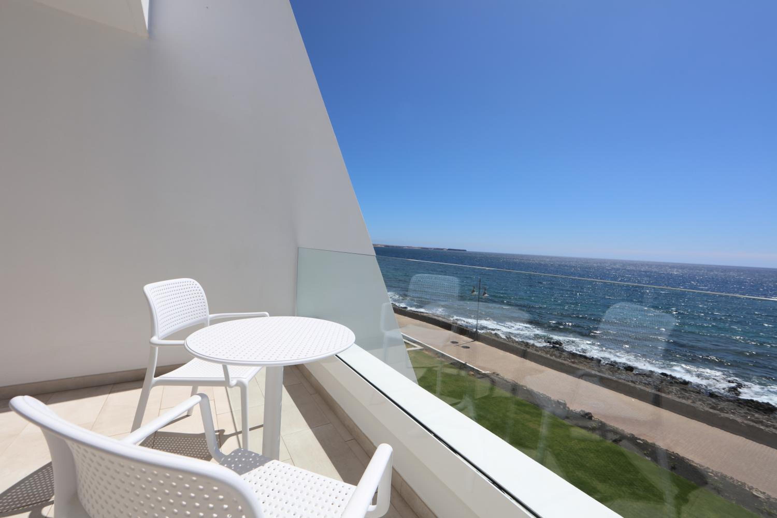 balcony with a table and chairs overlooking the ocean?