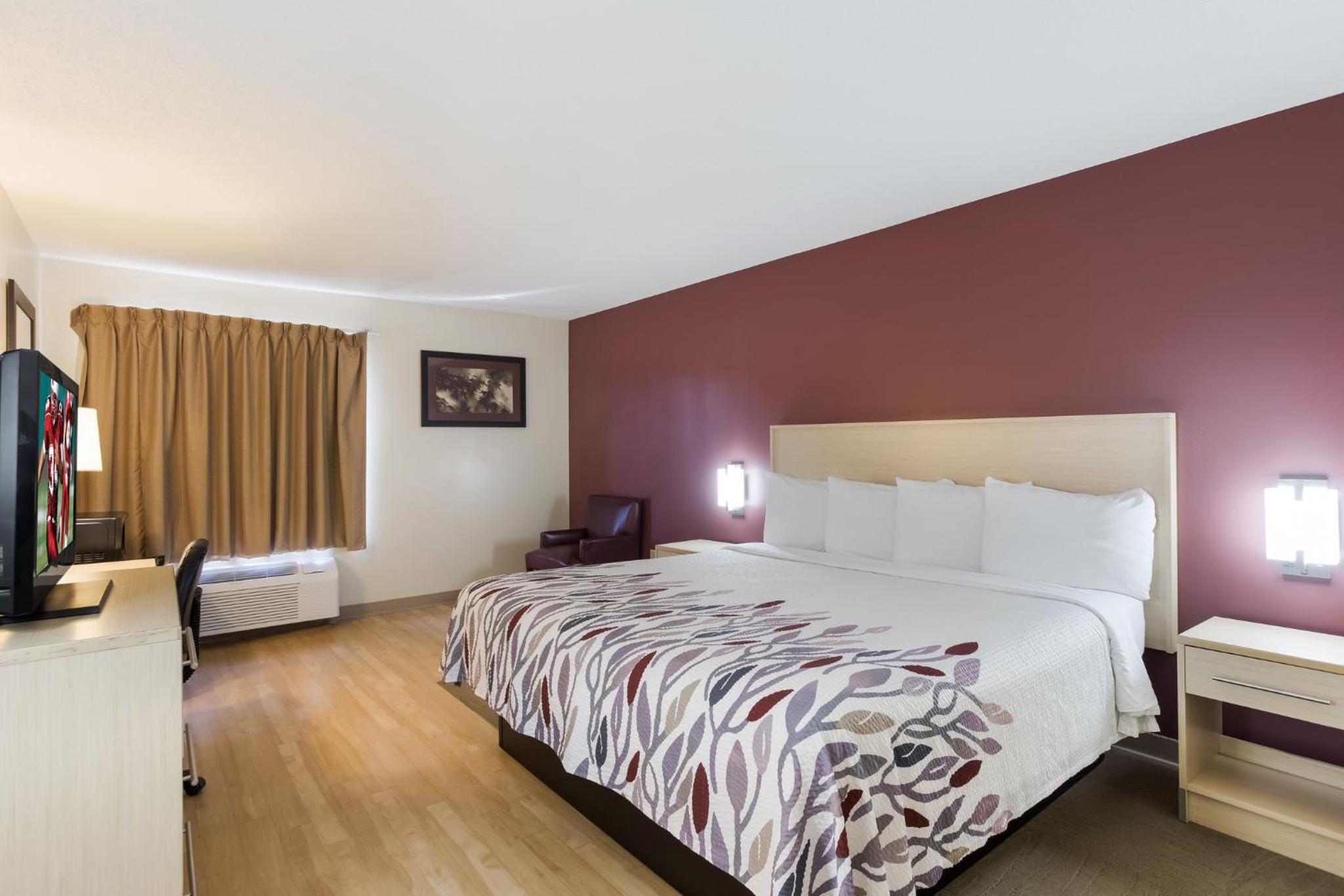 hotel room with a bed, desk, and television