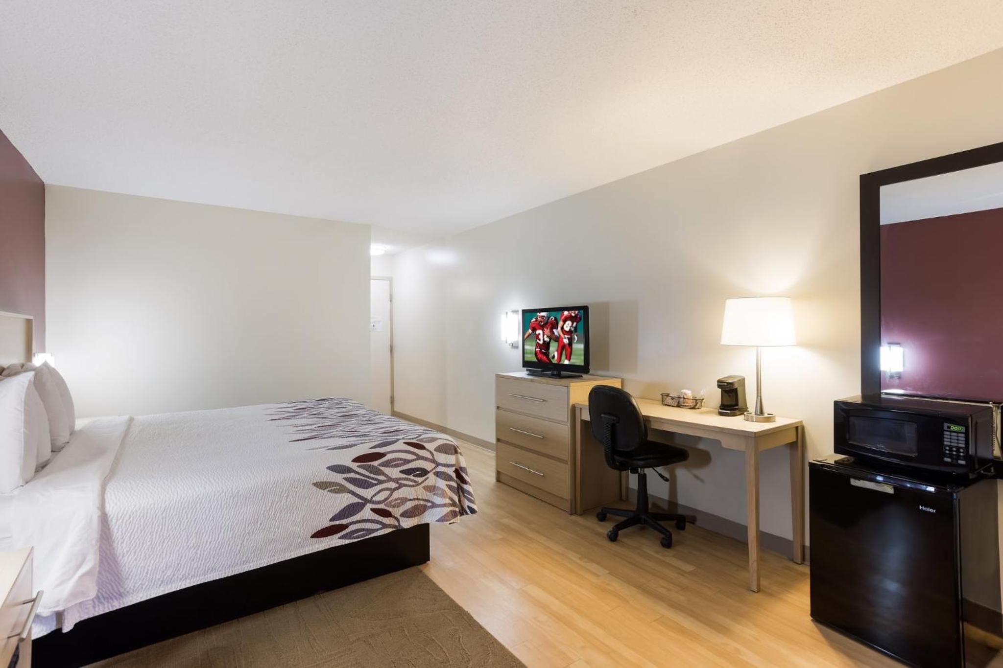 hotel room with a bed, desk, and television