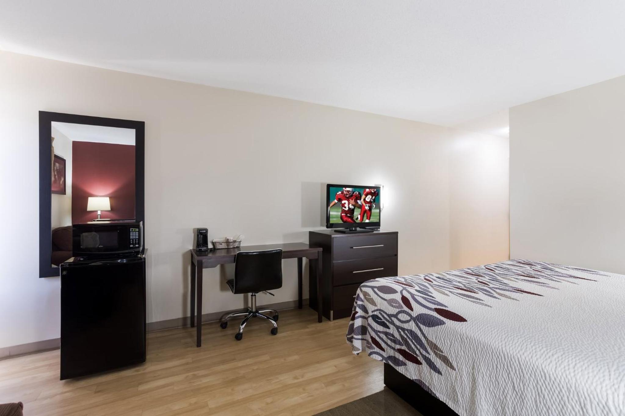 hotel room with a bed, desk, and television