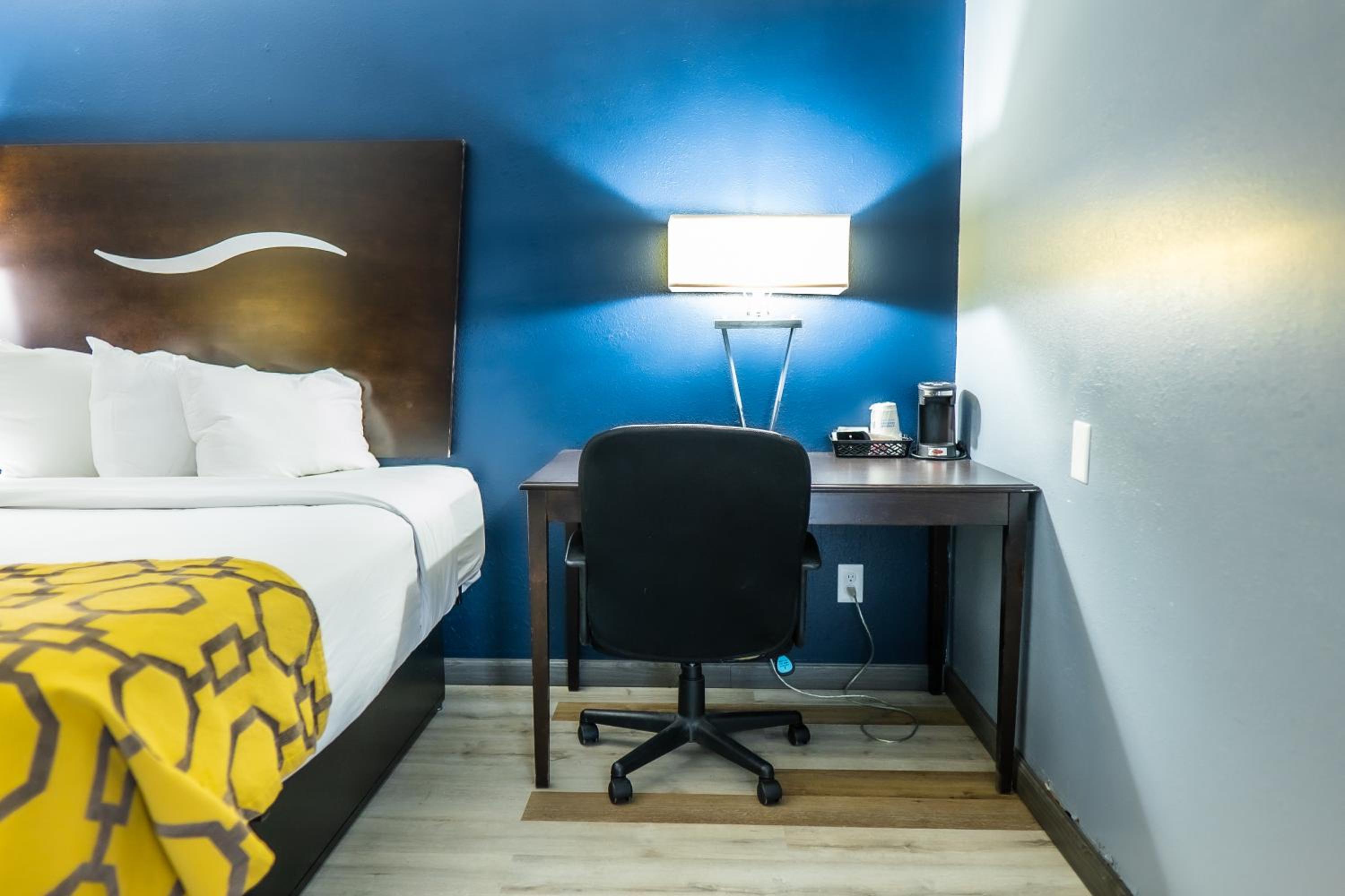 hotel room with a bed, desk, and lamp