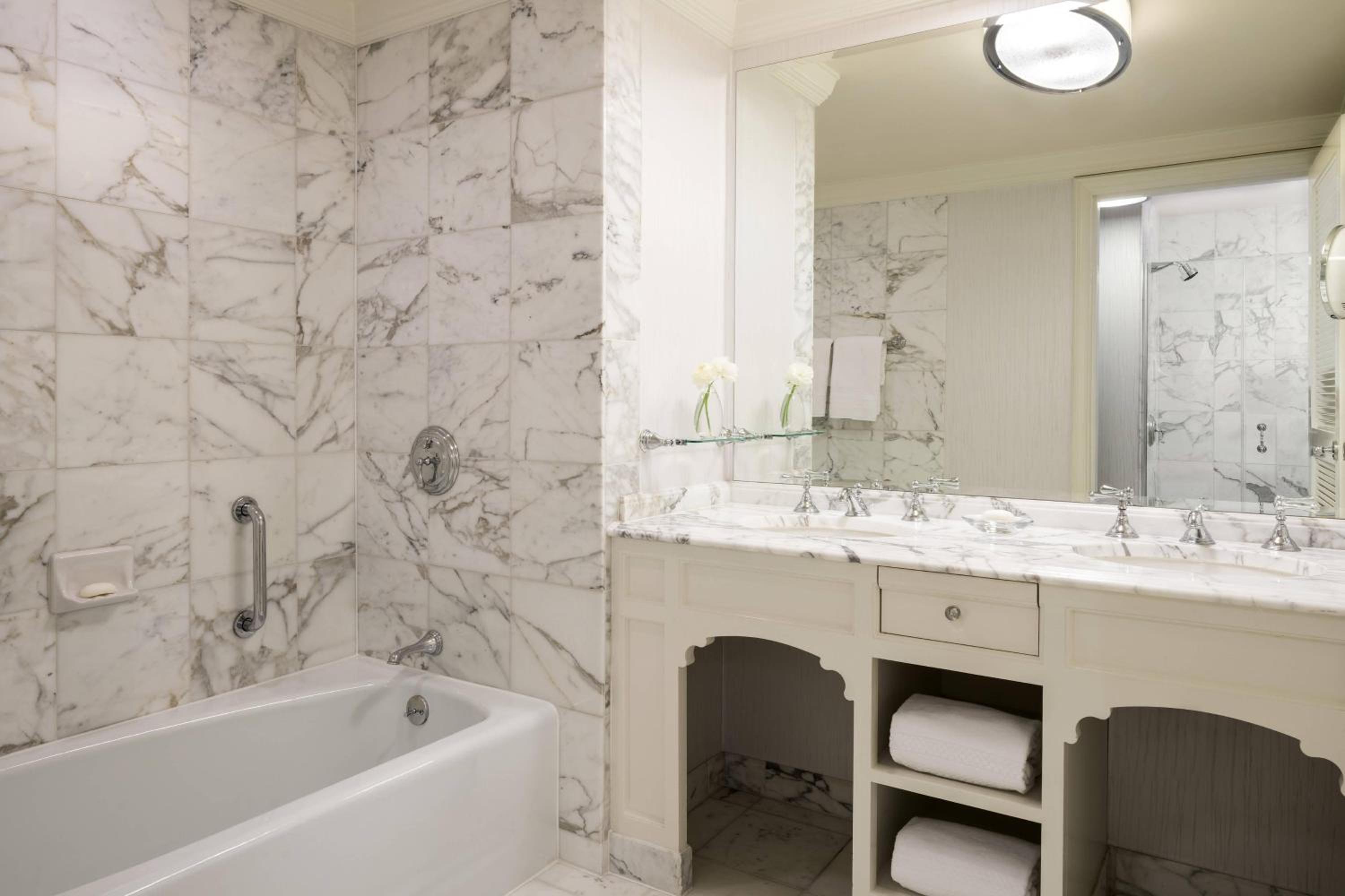 marble bathroom with a bathtub, sink, and mirror
