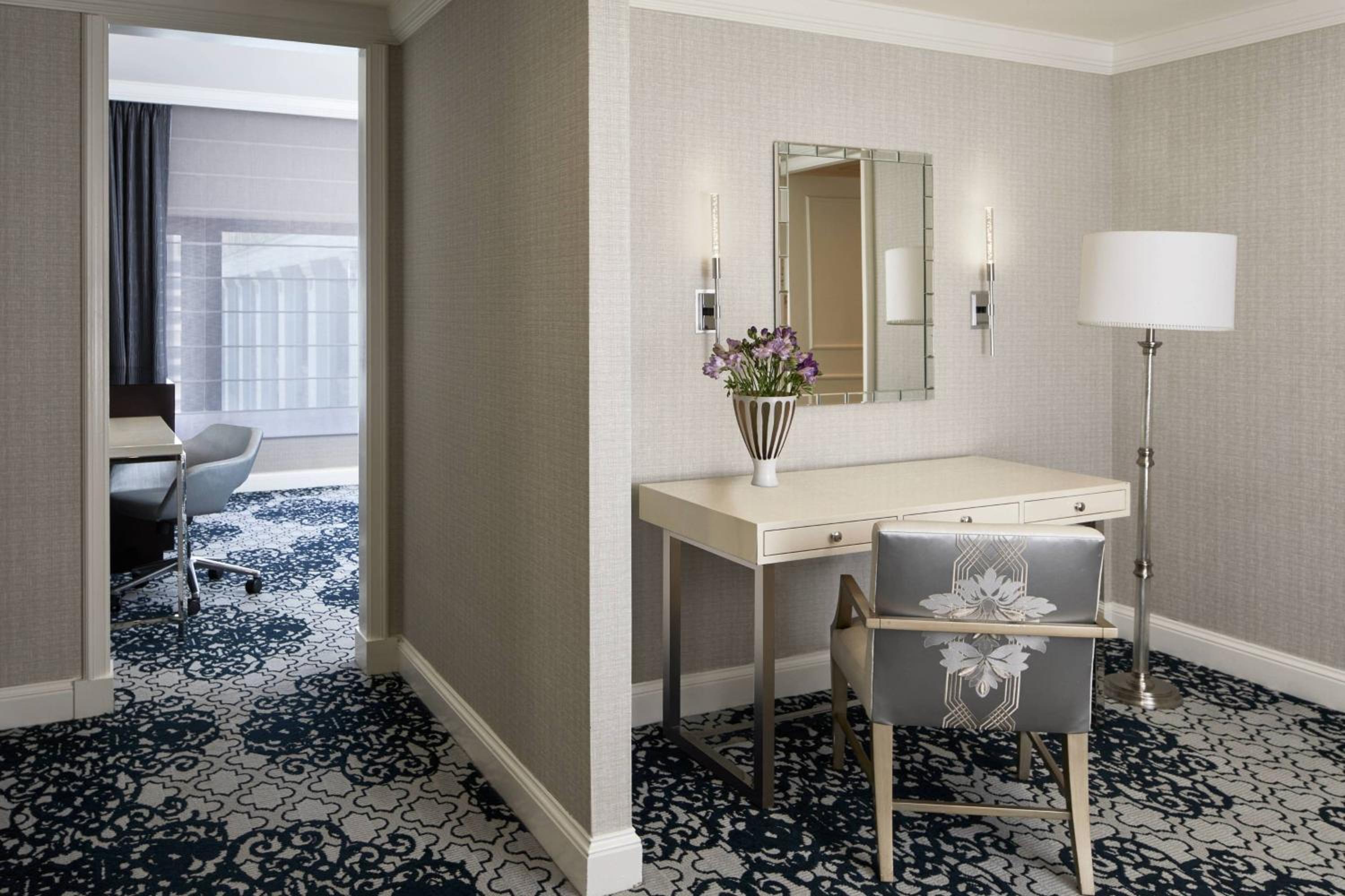 hotel room with a desk, chair, and mirror