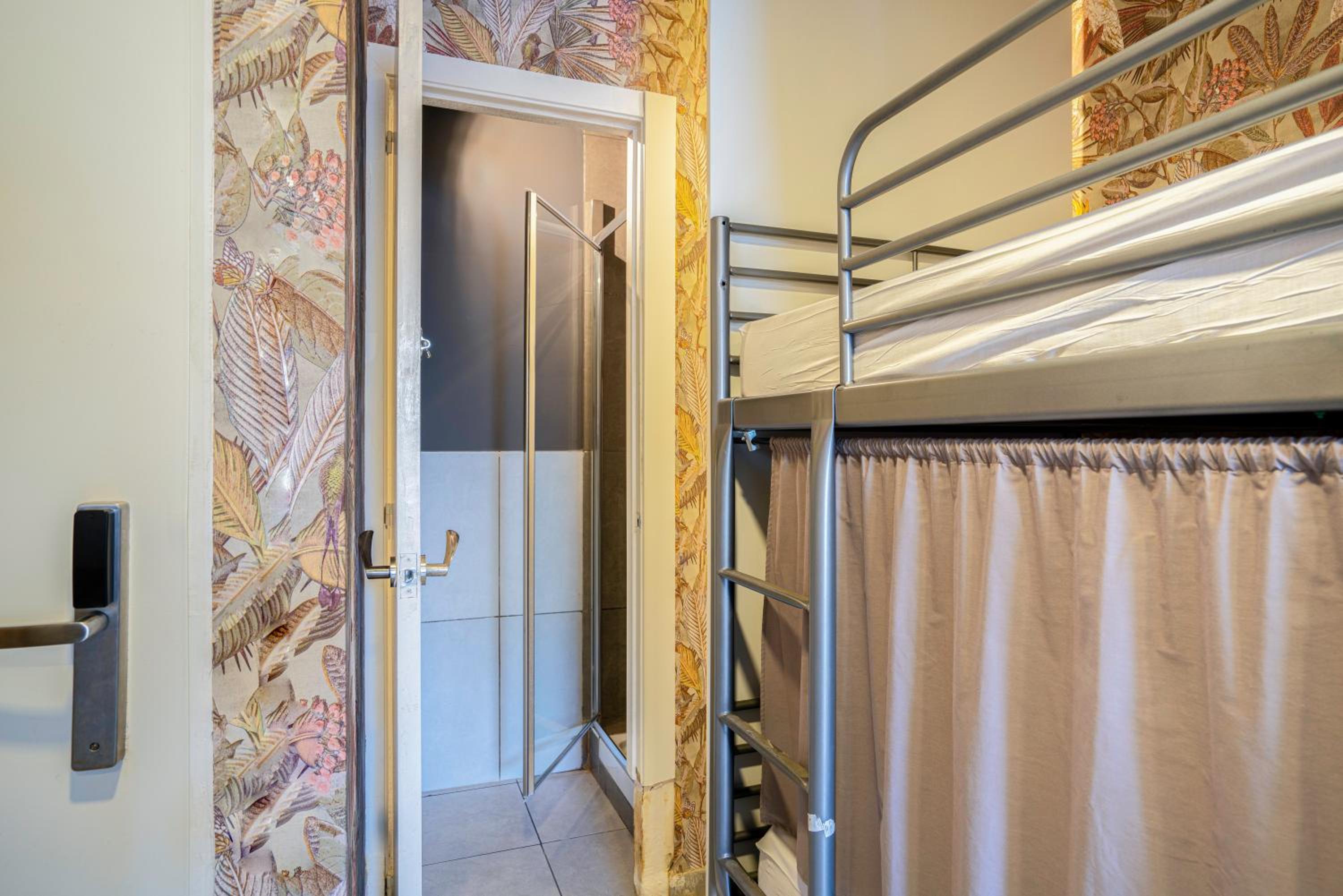 Cama en habitación compartida mixta de 6 camas con baño privado y balcón.