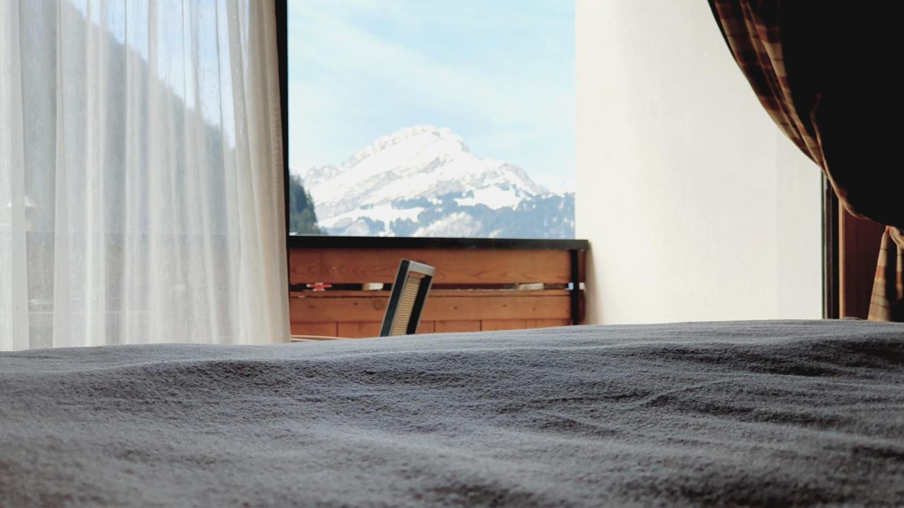 Bed surface foreground with balcony and snowy mountain view through window