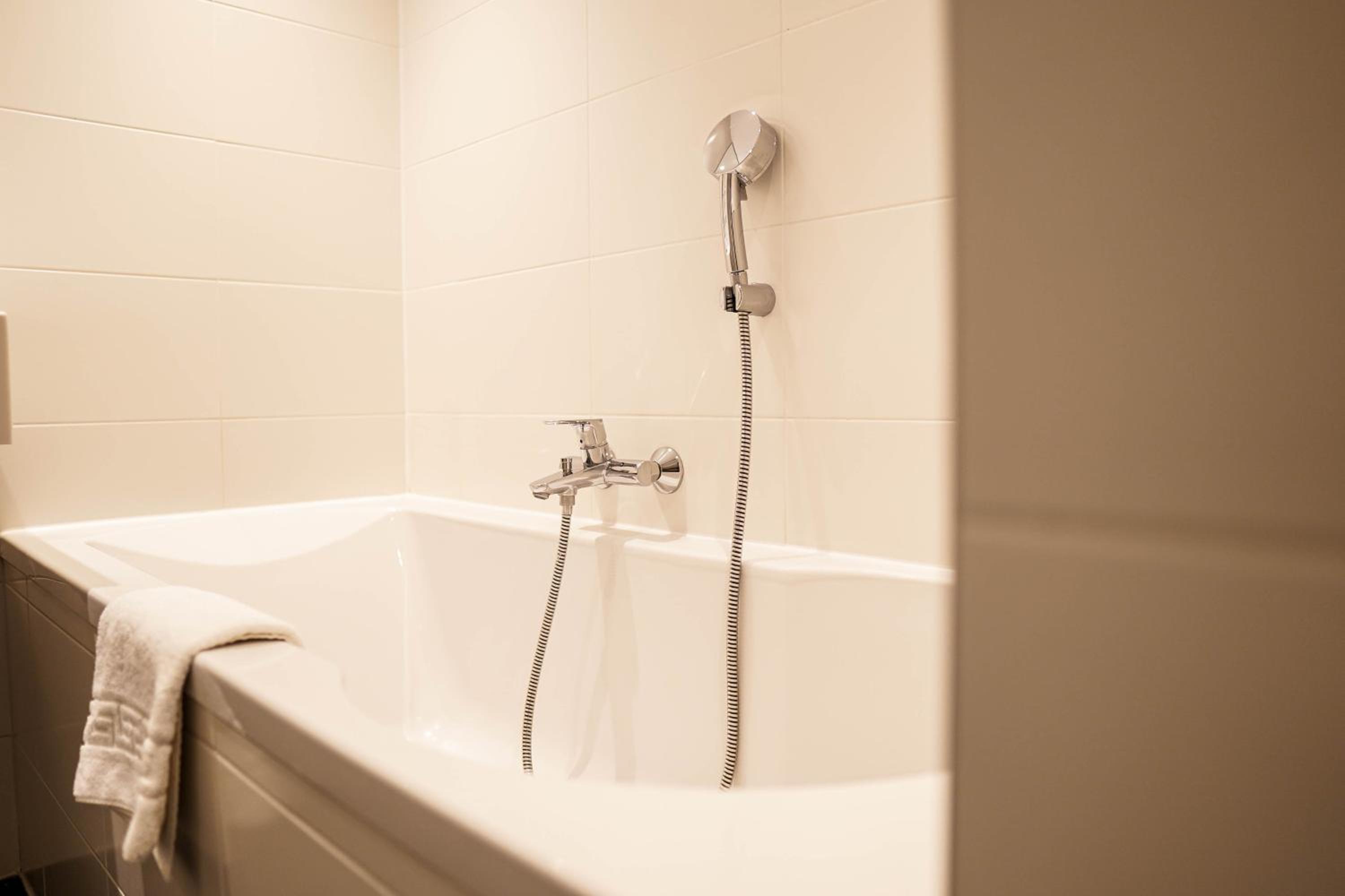 white bathtub with a shower head and handset
