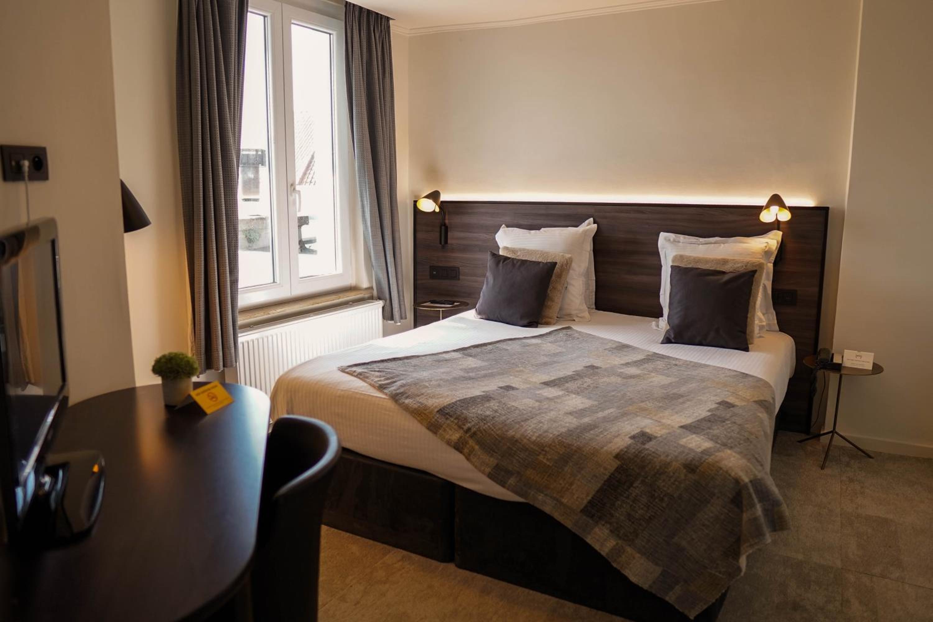 hotel room with a bed, desk, and window
