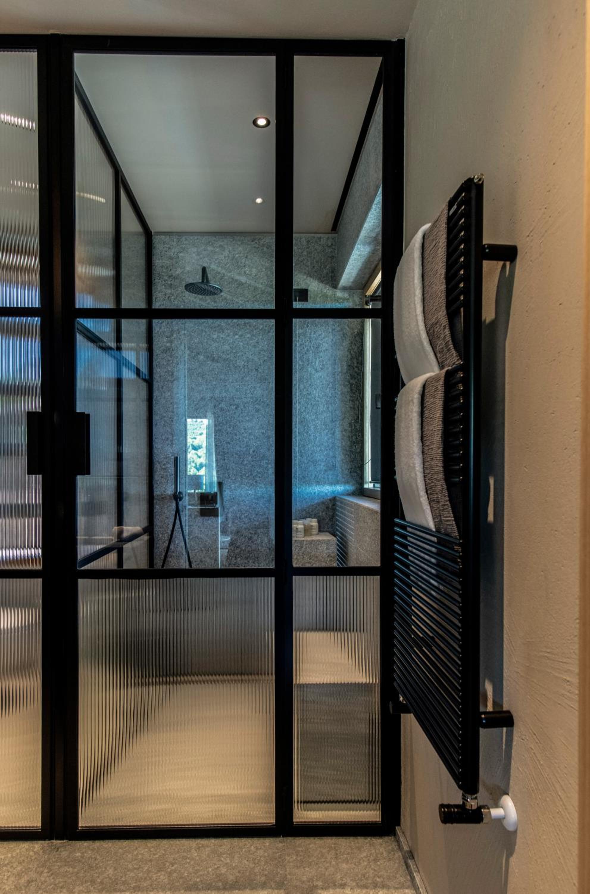 bathroom with glass walls and a toilet in the corner