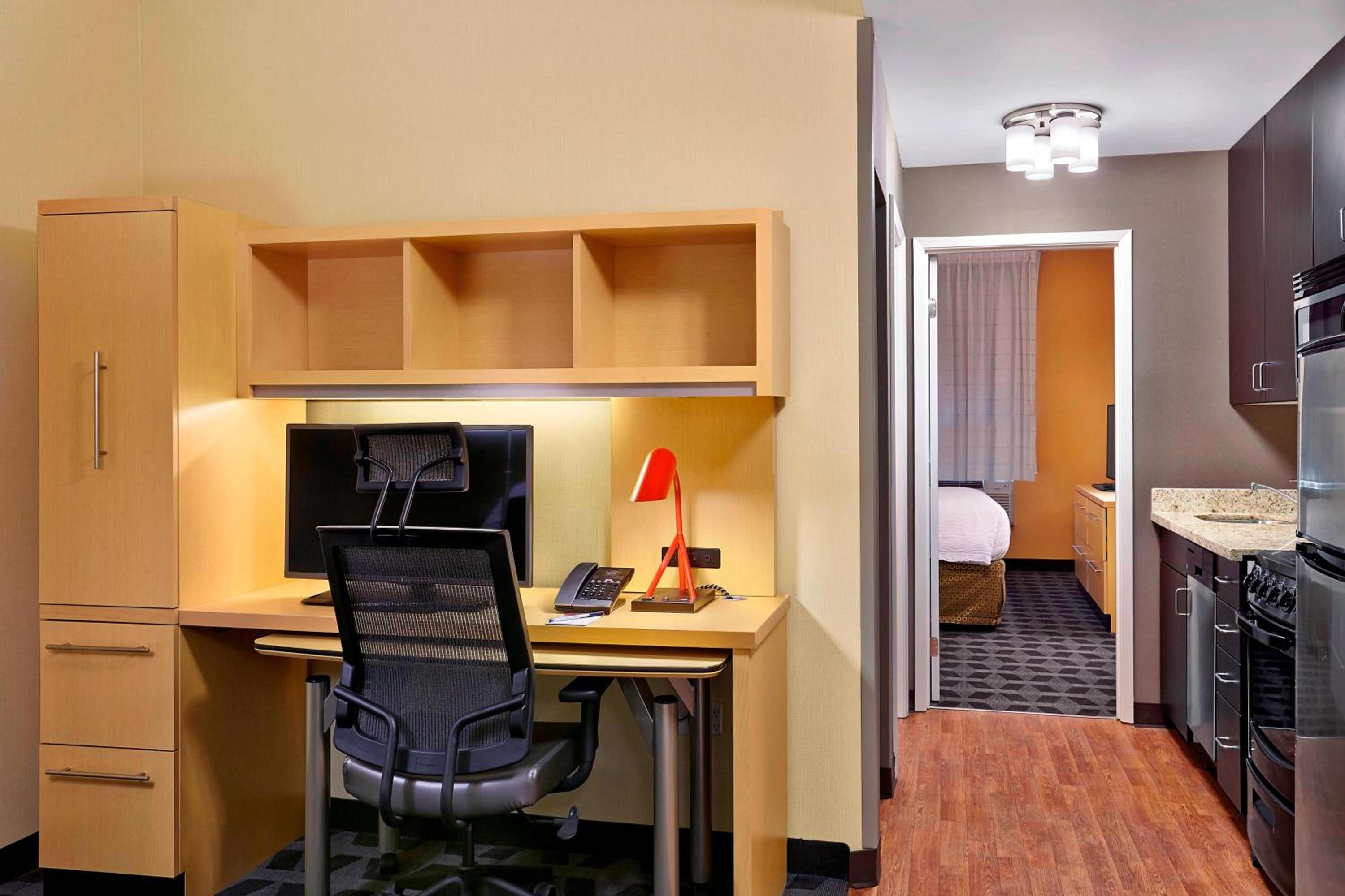room with a desk, microwave, and refrigerator in it