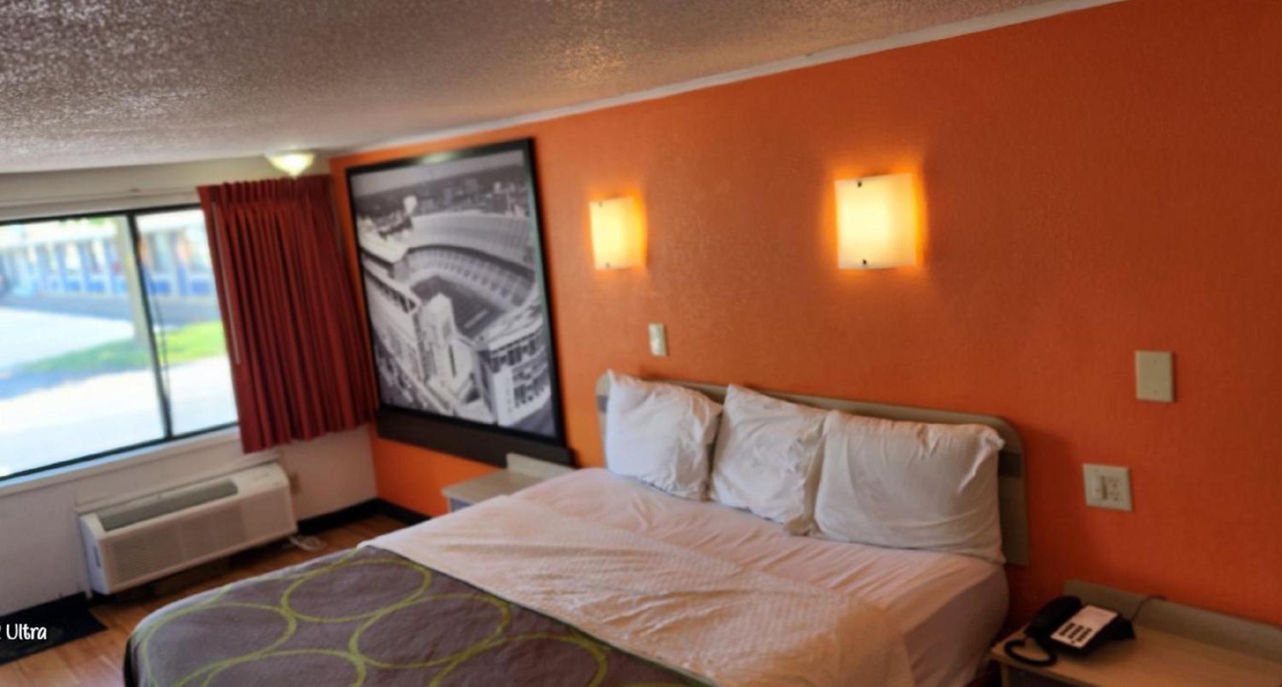 hotel room with orange walls and a king size bed
