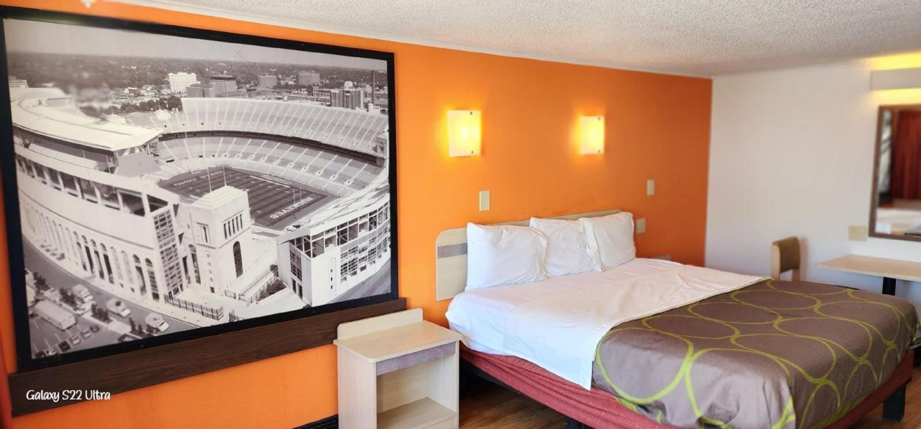 hotel room with orange walls and a large picture on the wall