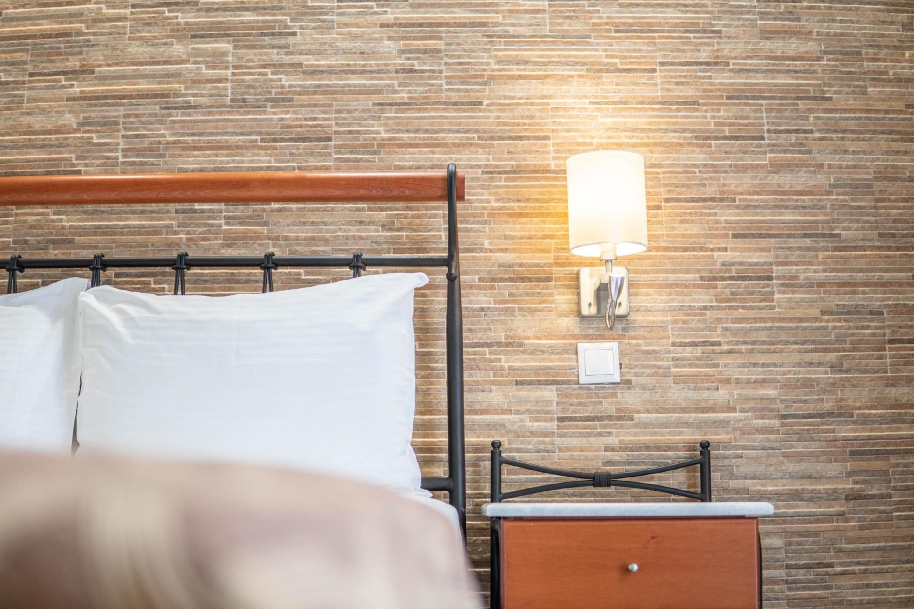 Bedroom with a metal and wood headboard, white pillows, and a stone wall.