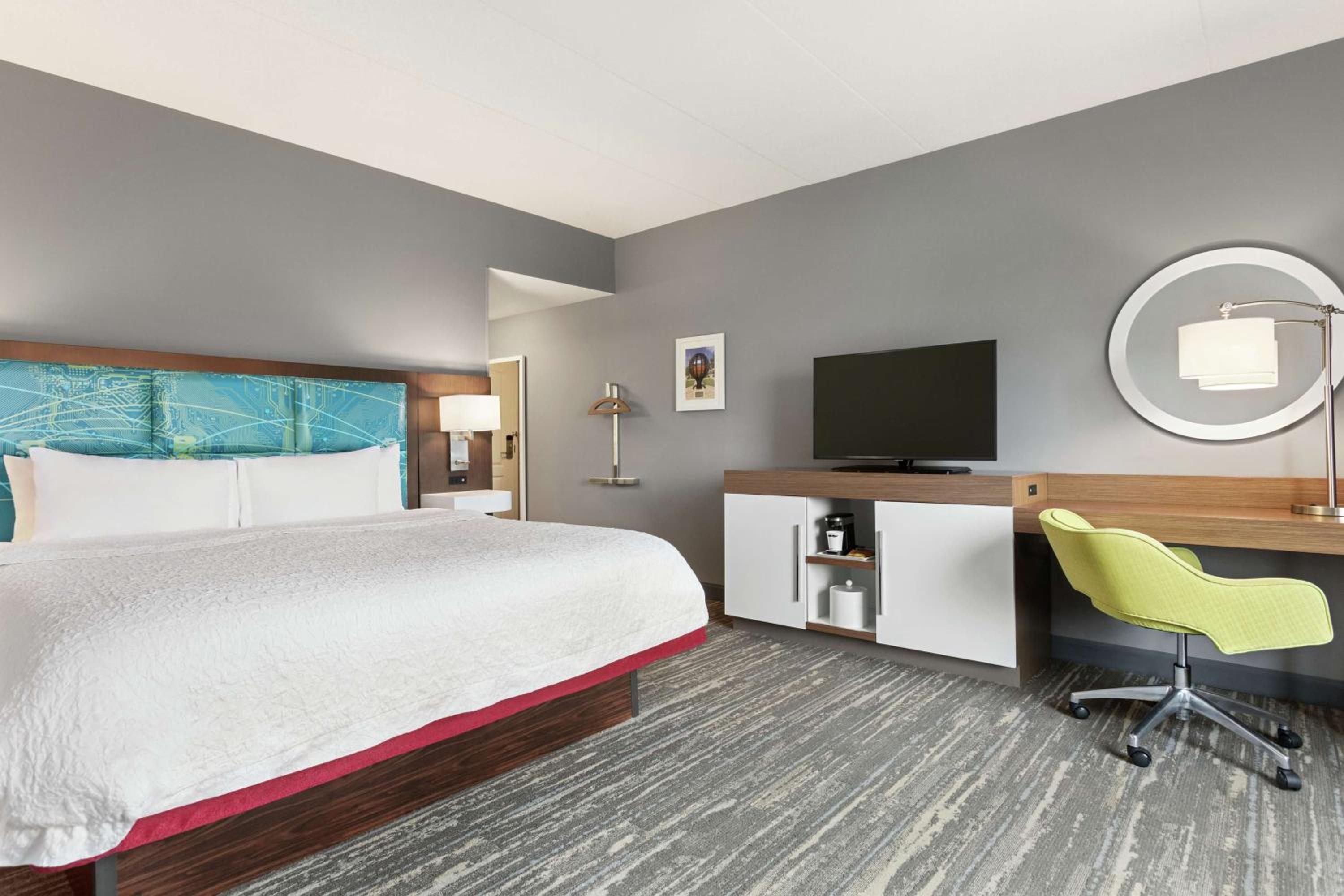 hotel room with a bed, desk, and television