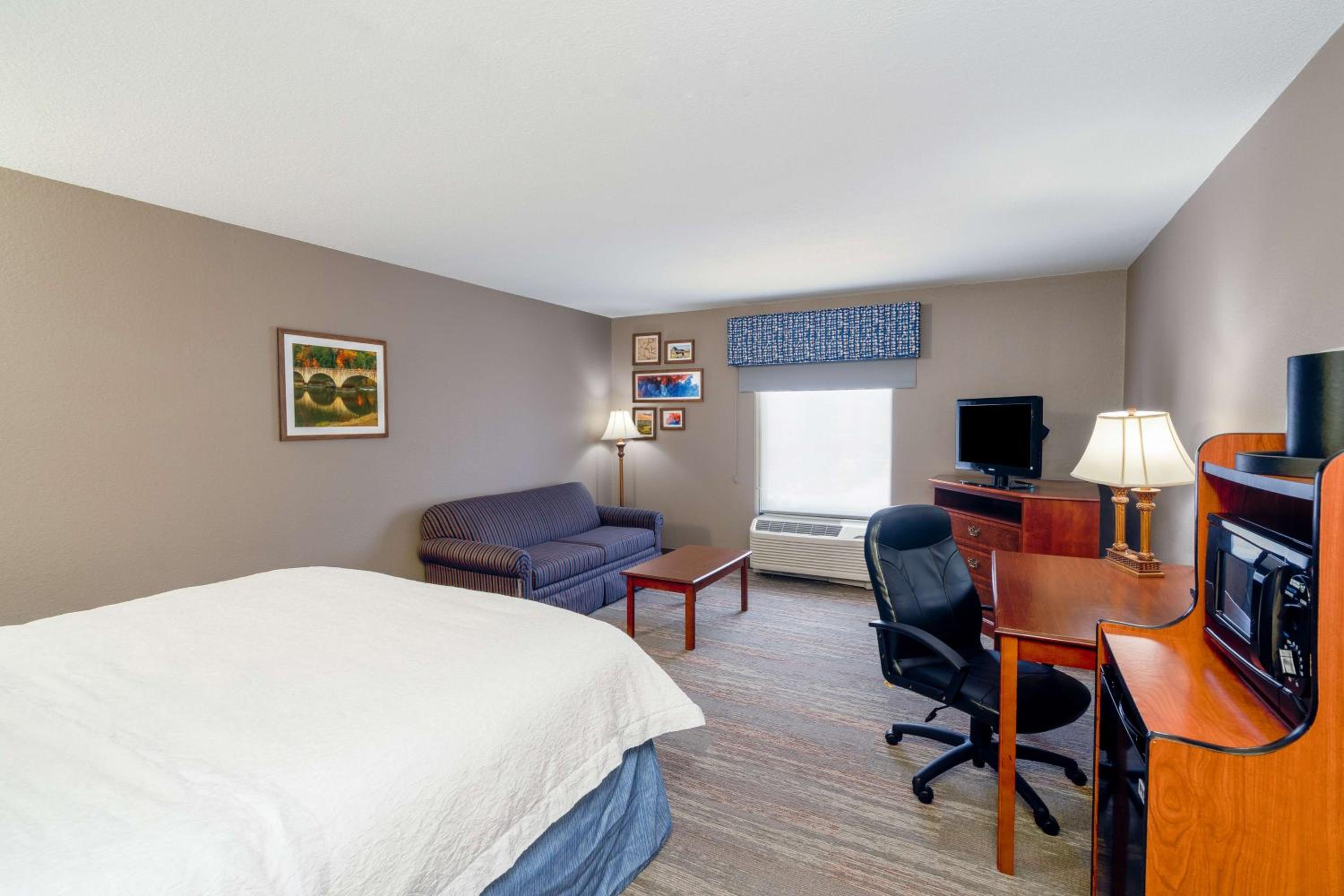 hotel room with a bed, desk, and television