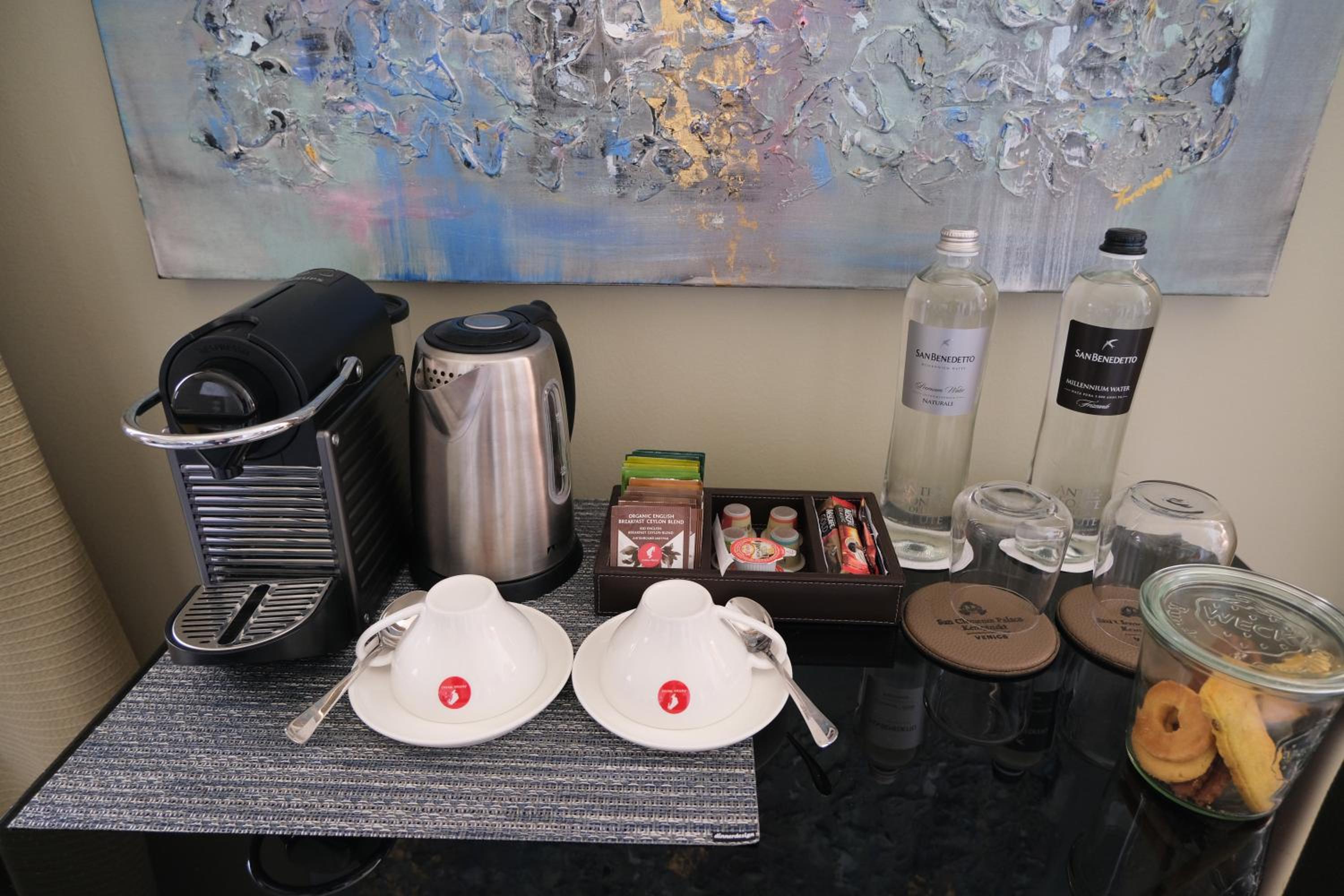 coffee maker, cups, and donuts on a table