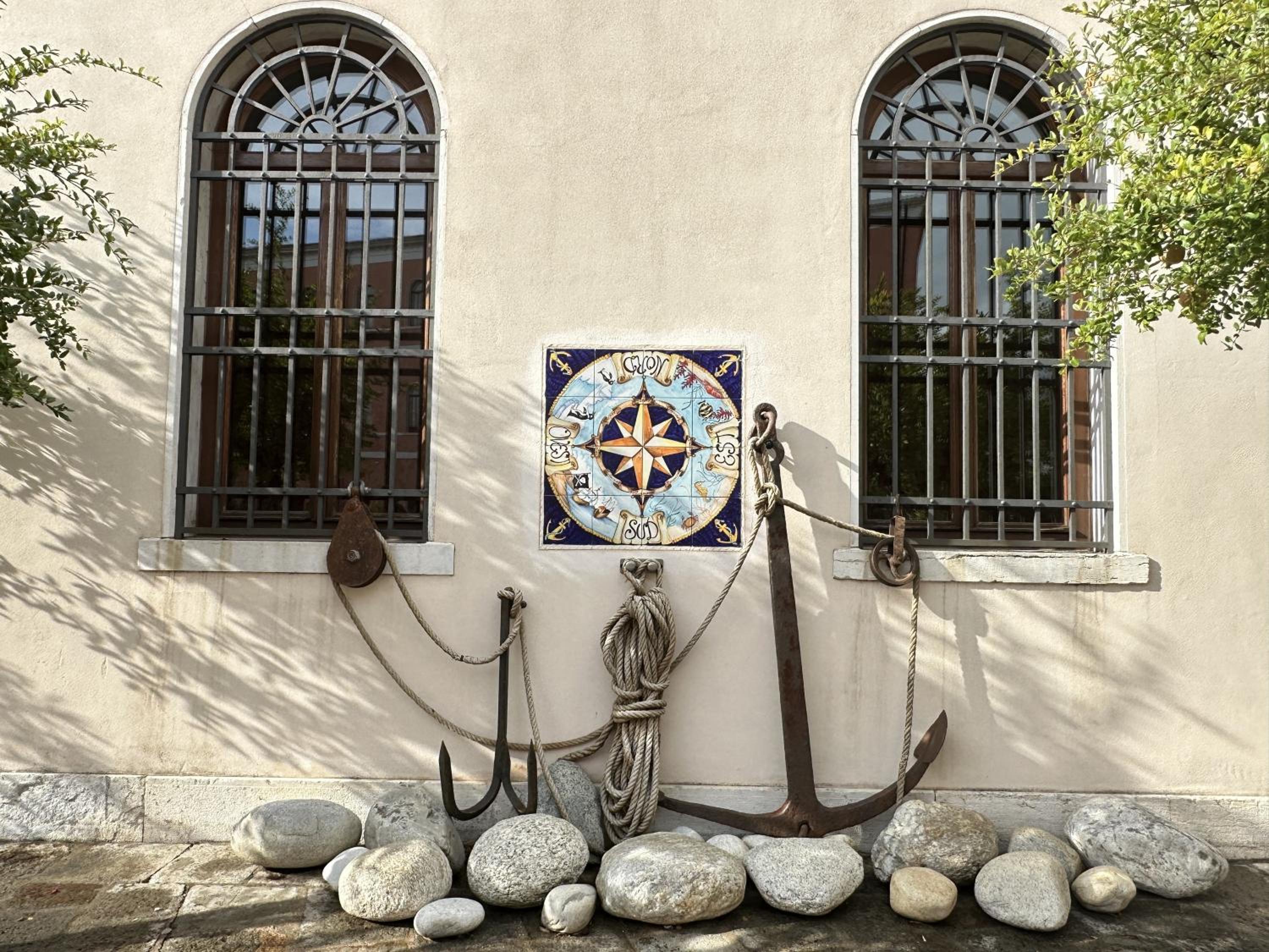 nautical themed clock and anchor on the side of a building