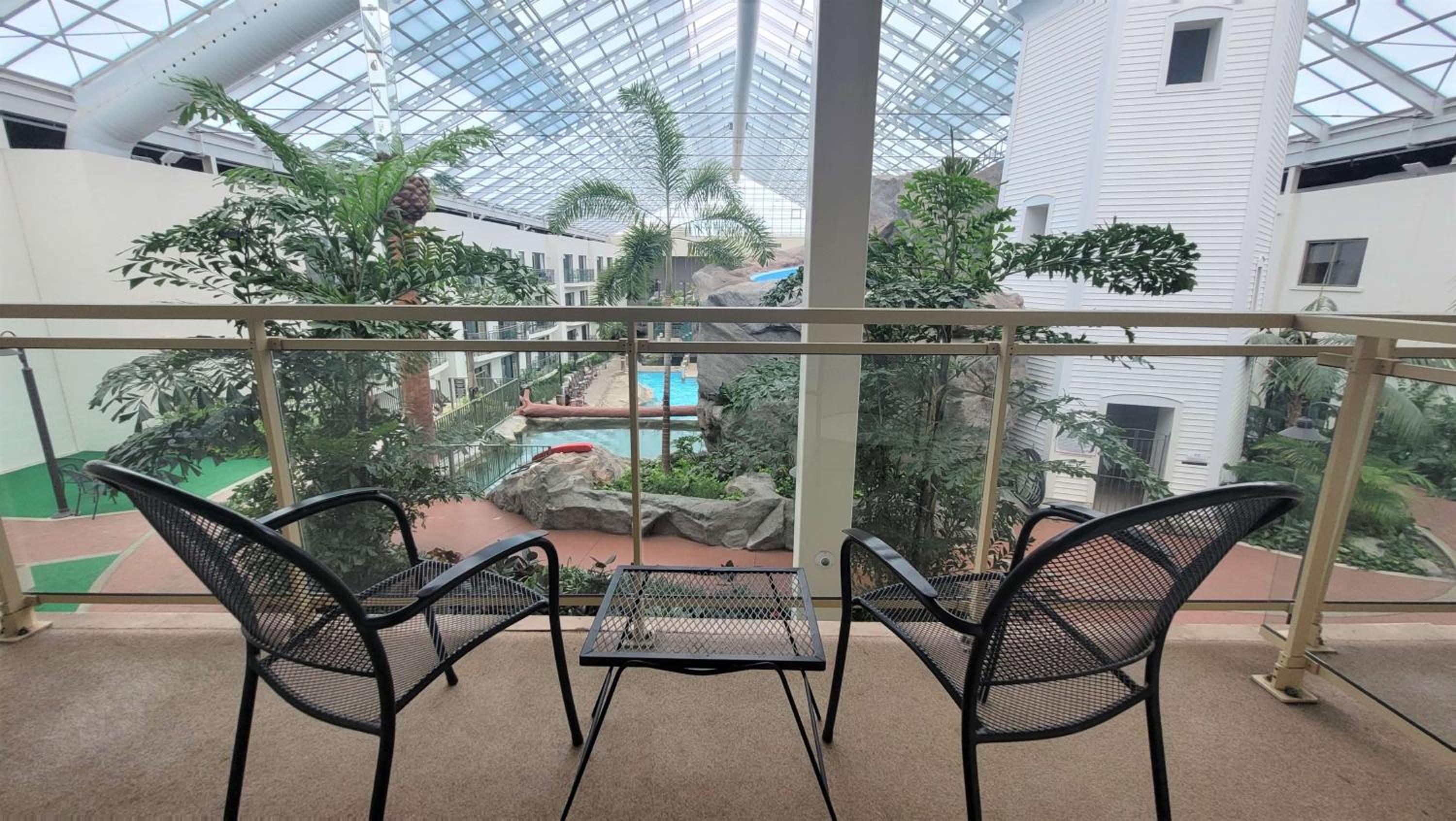 balcony with two chairs and a table overlooking a pool
