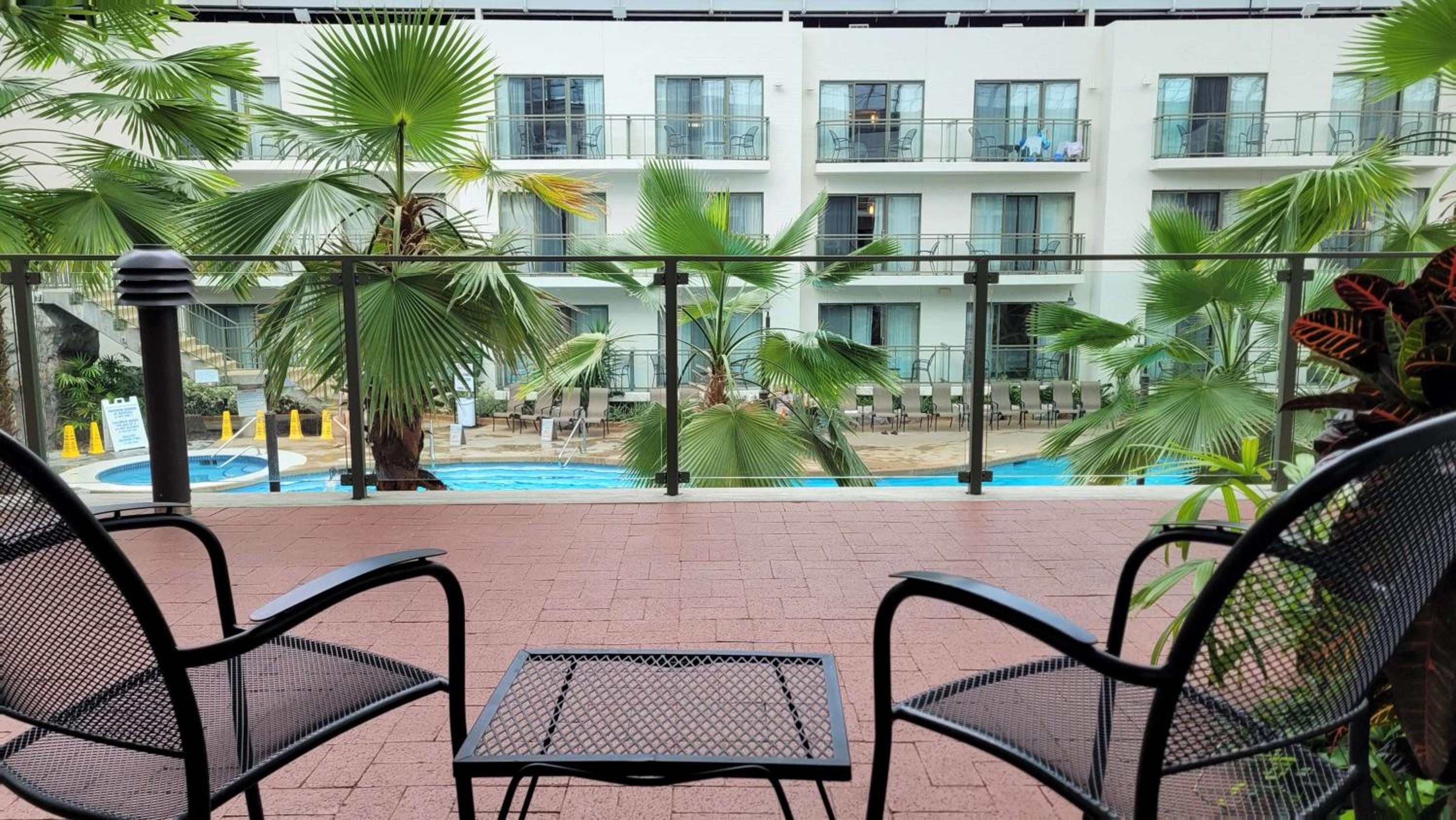 balcony with two chairs and a table overlooking the pool