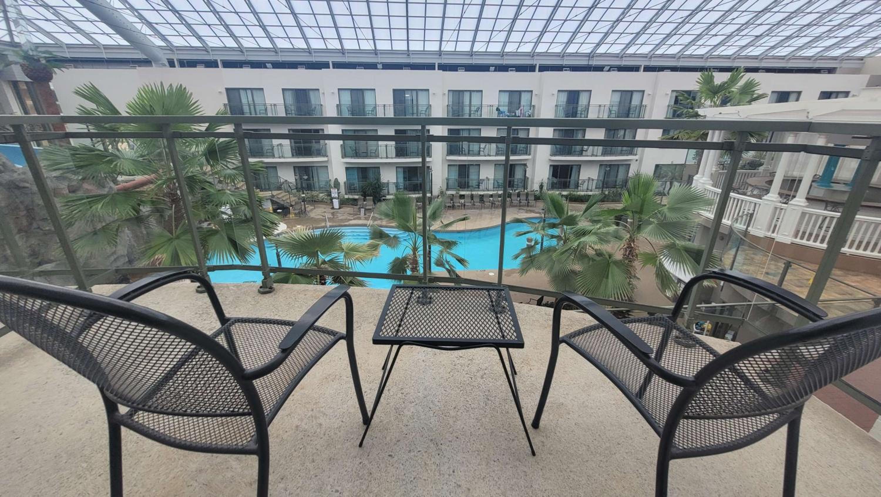 balcony with two chairs and a table overlooking the pool