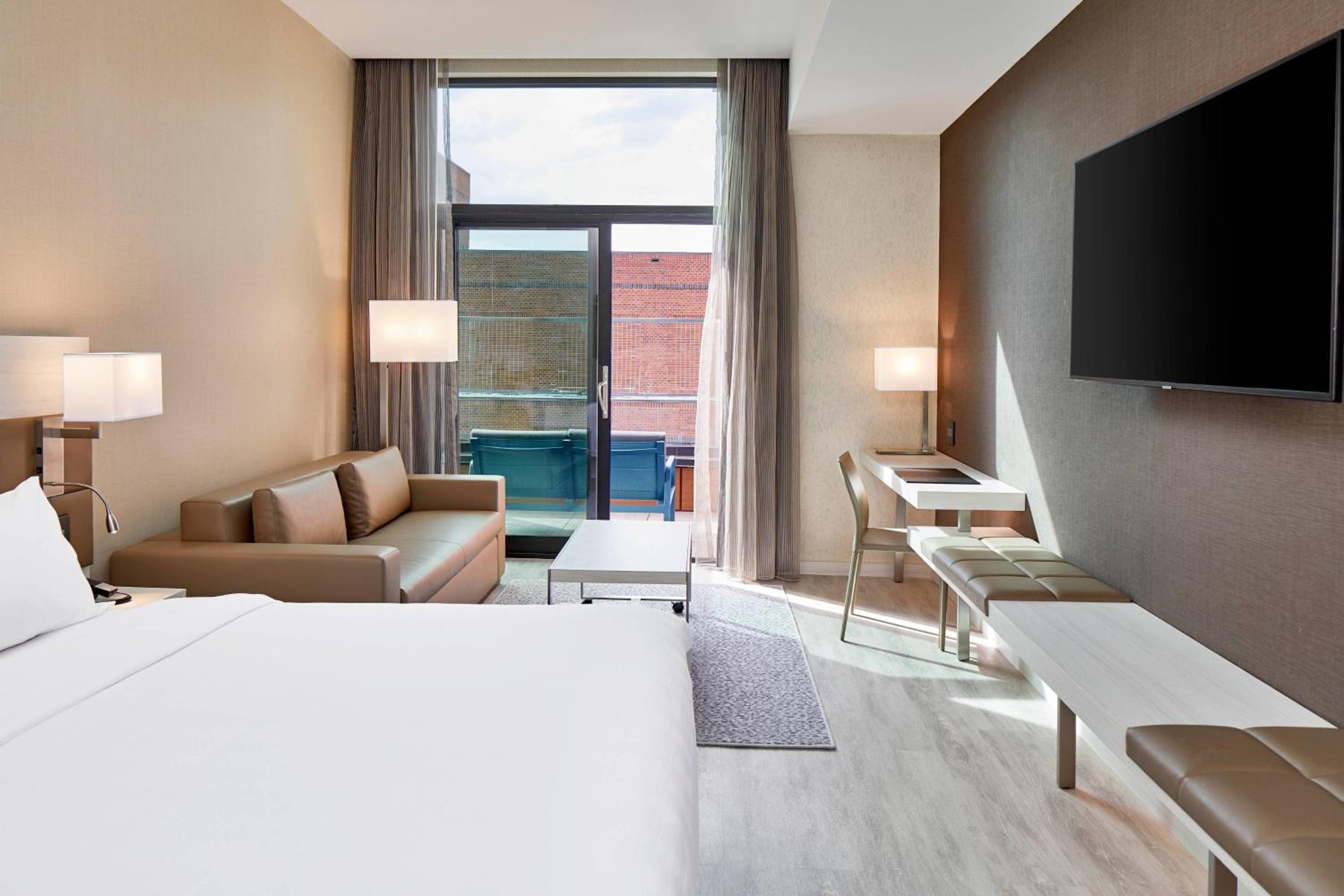 Guest room with king bed, sofa bed, balcony and city view