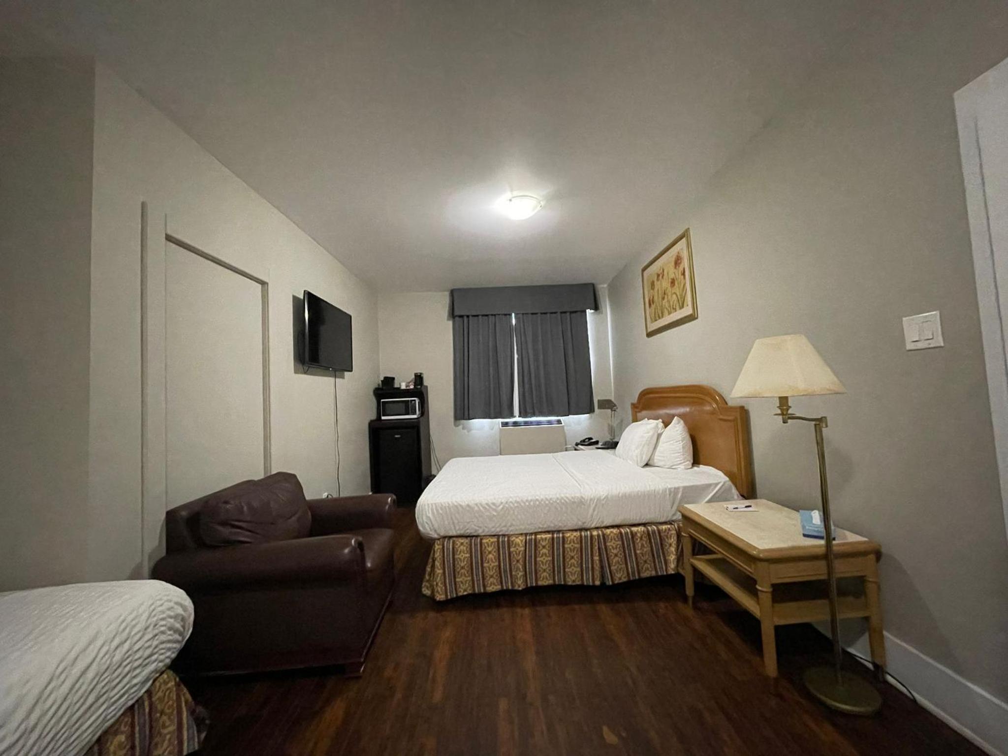 hotel room with two beds, a couch, and a flat screen tv