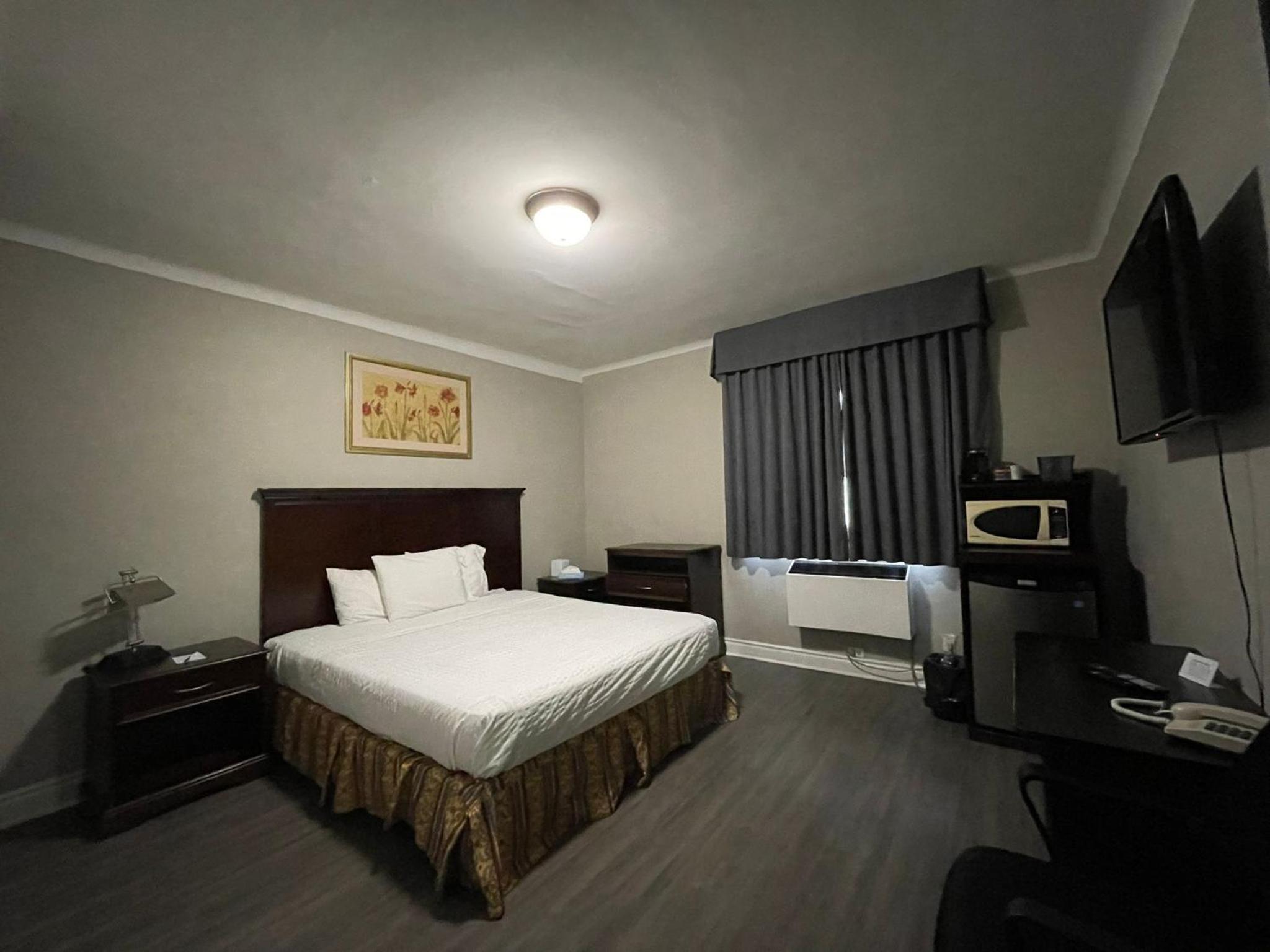 hotel room with a bed, desk, and television
