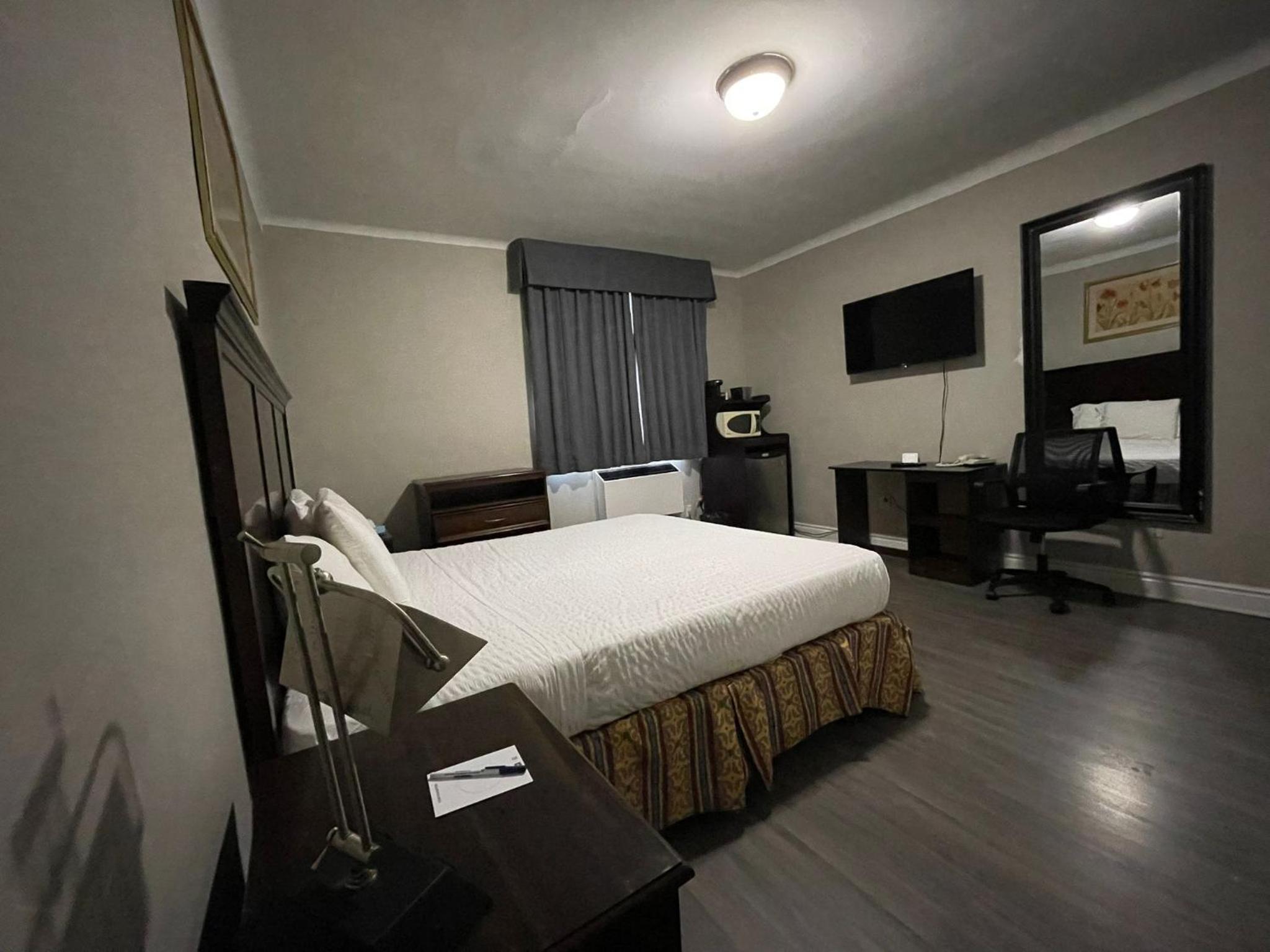 hotel room with a bed, desk, and television