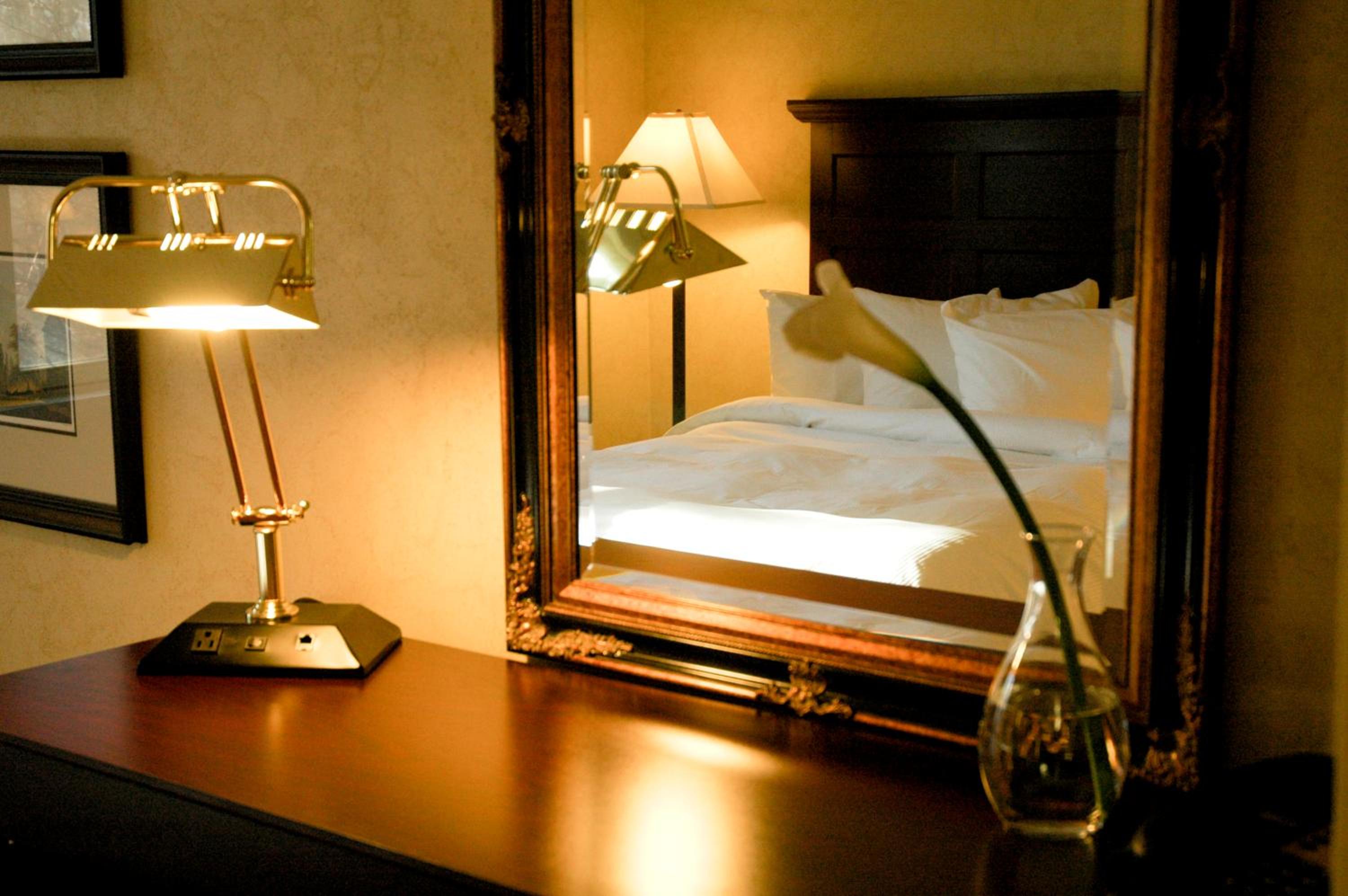 reflection of a bed in a mirror and a lamp