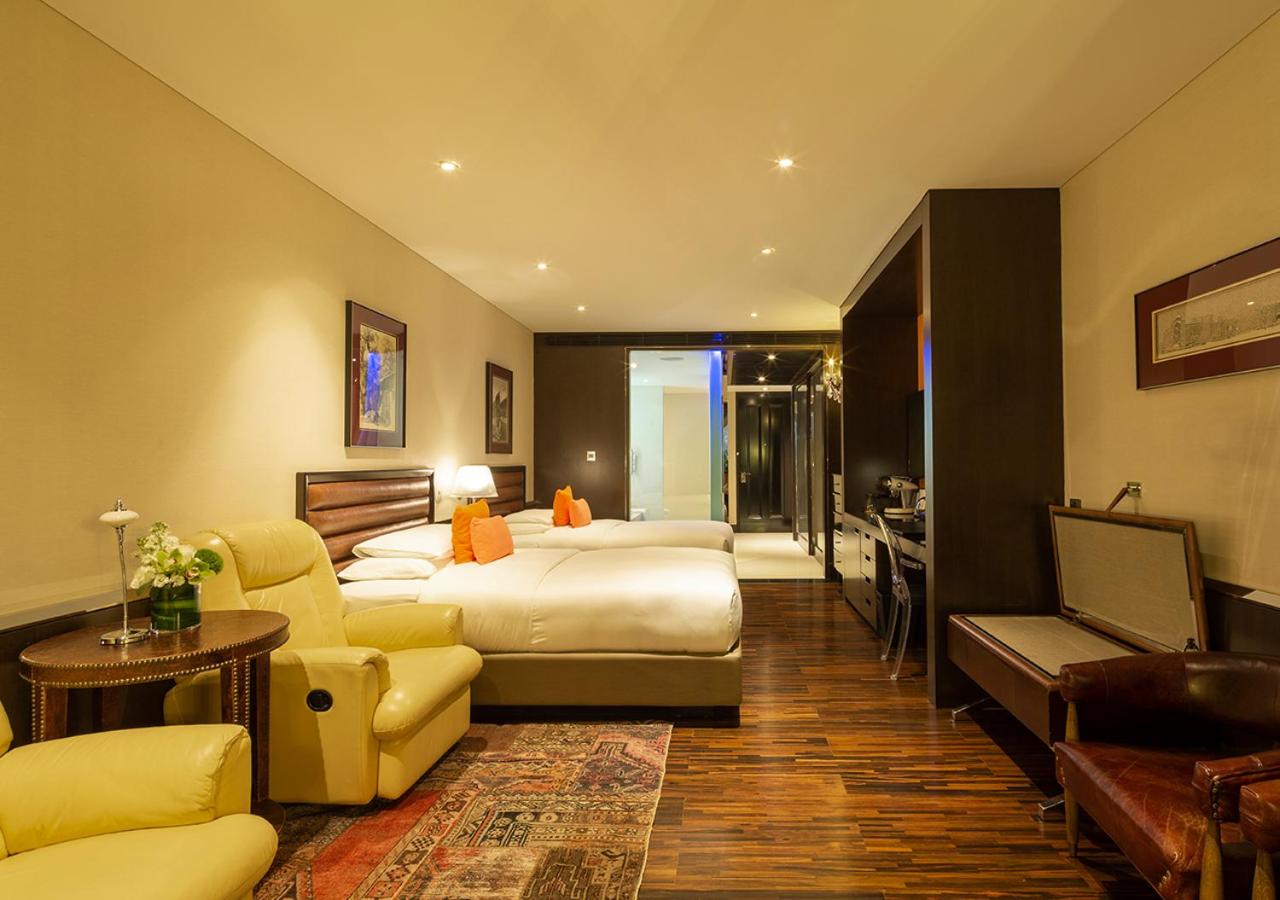 hotel room with two beds, couches, and a flat screen tv