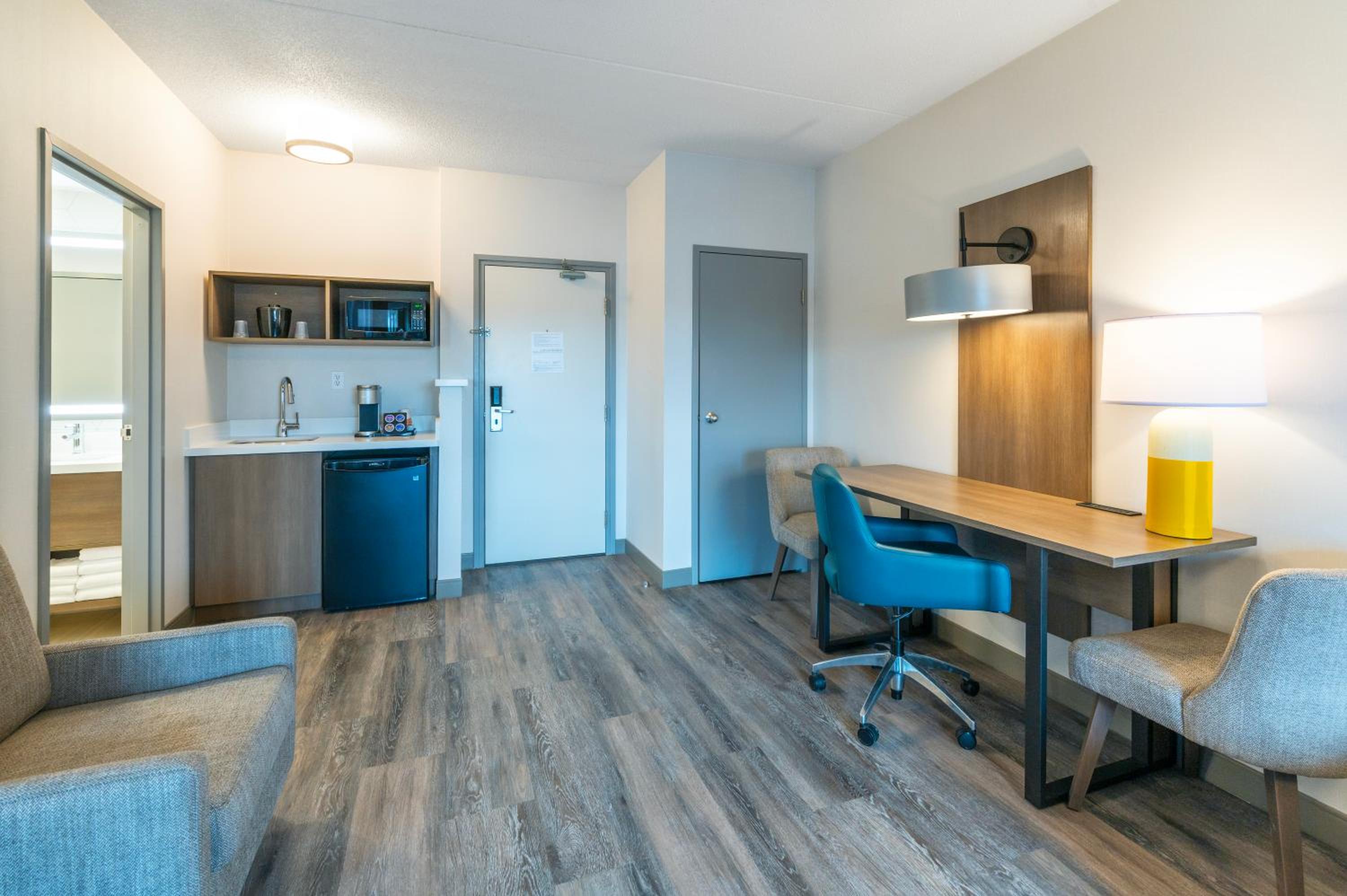 room with a desk, chair, and kitchenette