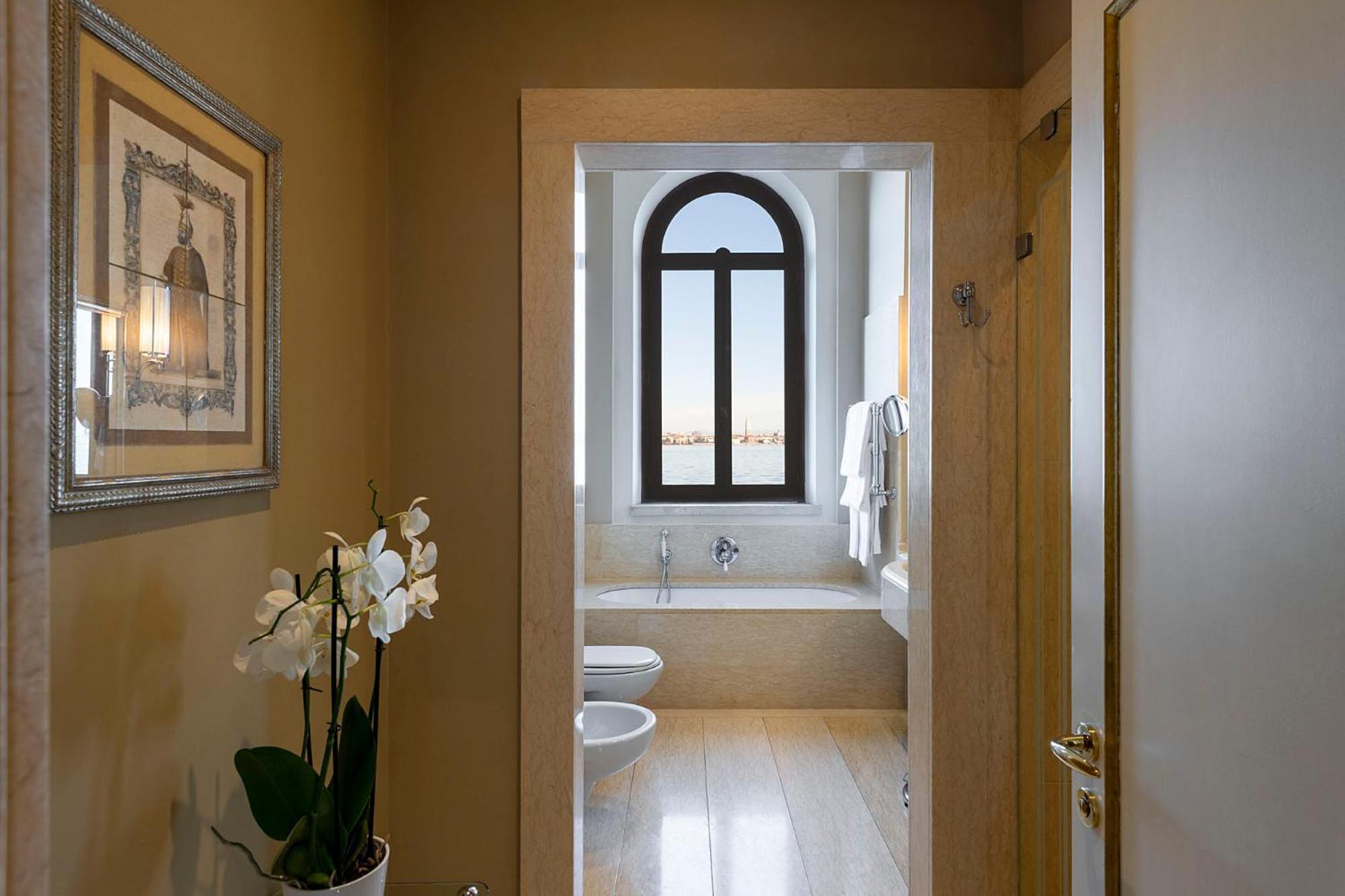 hallway leading to a bathroom with a tub and toilet
