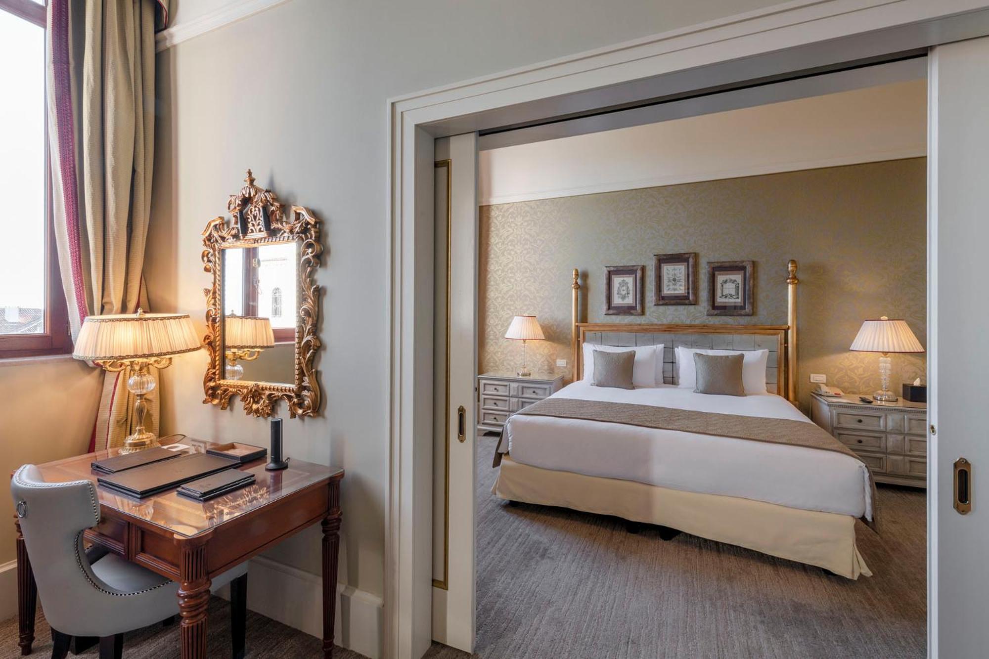 hotel room with a bed, desk, and mirror