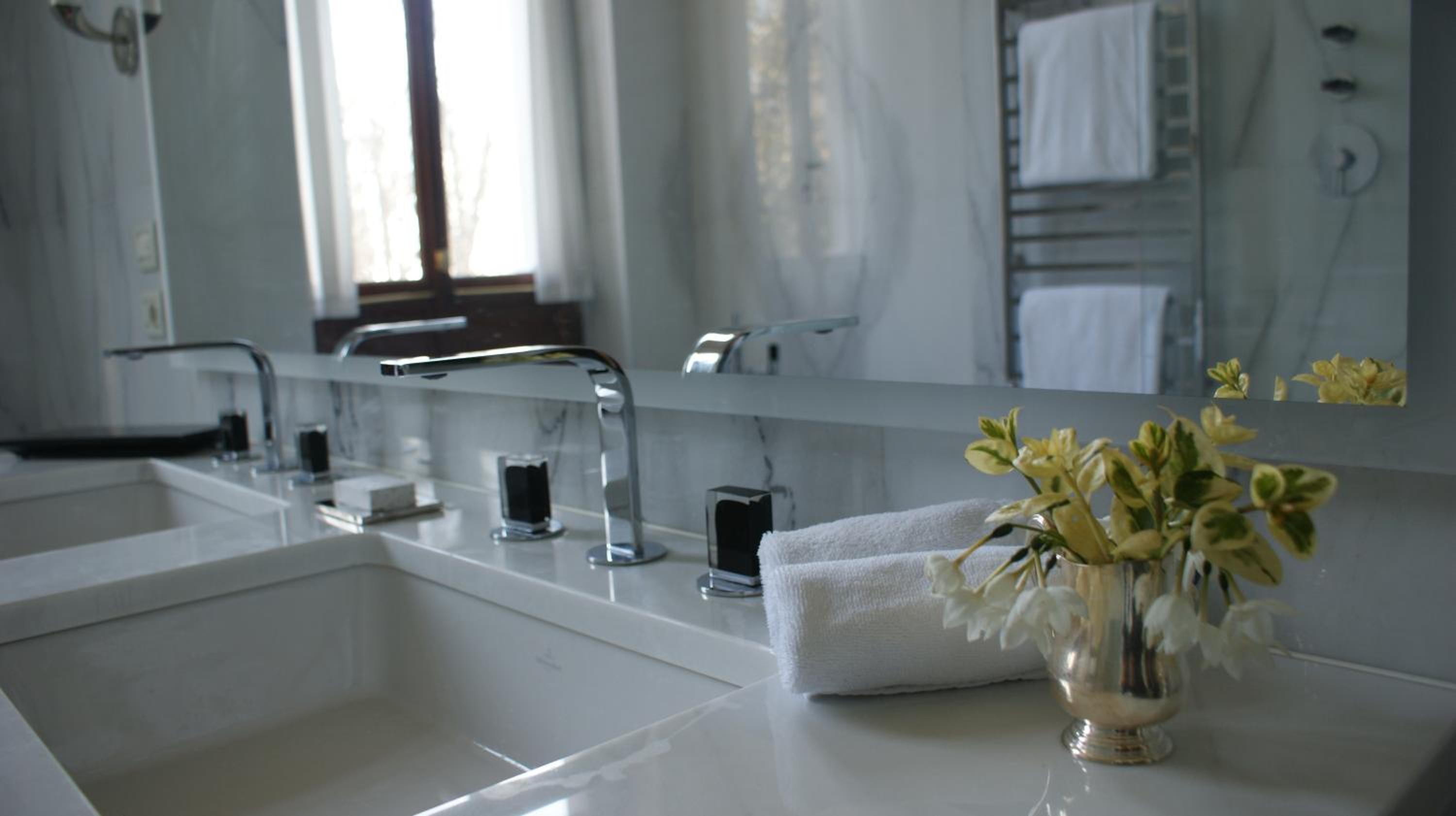 bathroom with two sinks and a vase of flowers on the counter