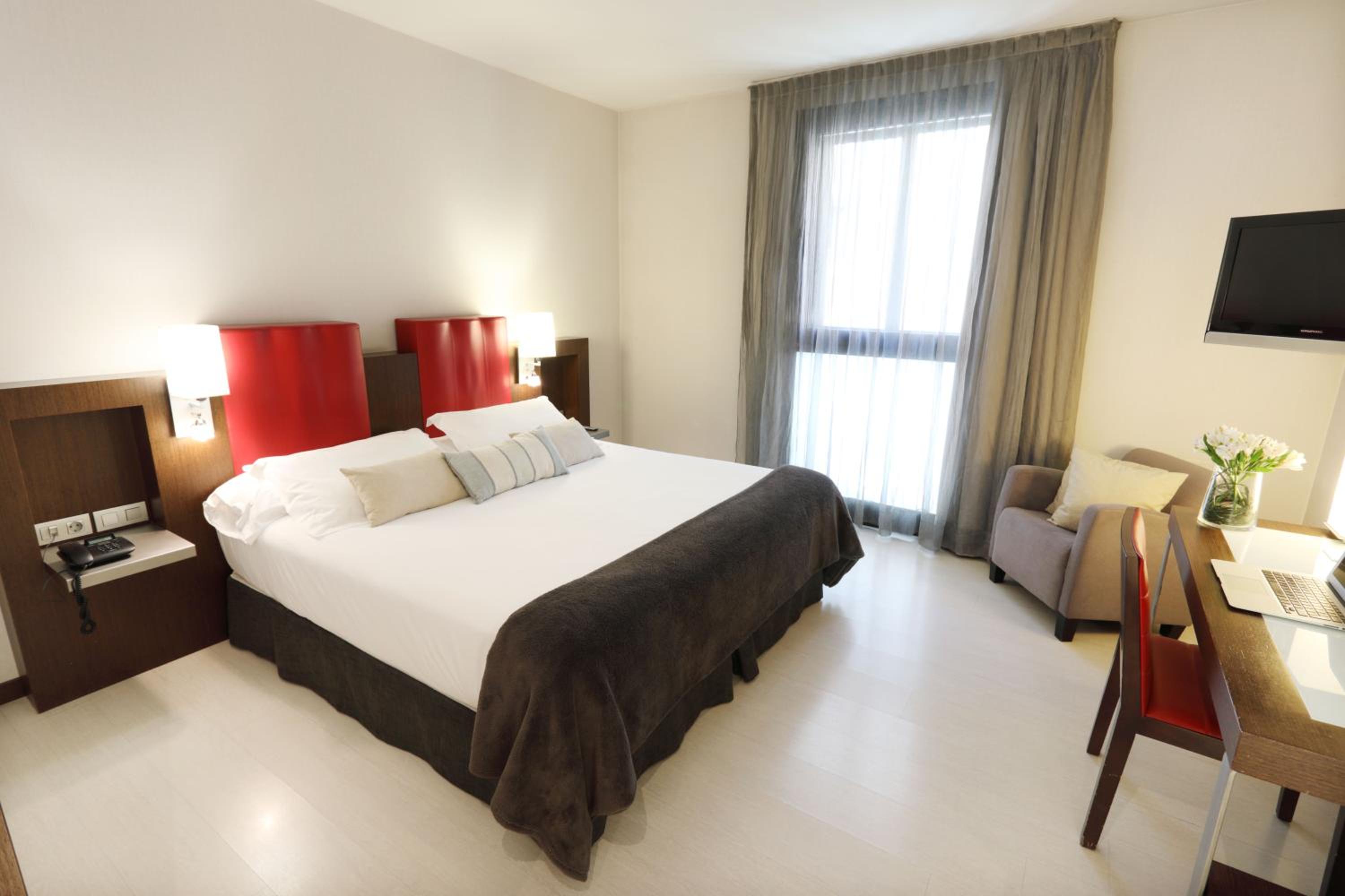 hotel room with a bed, desk, and television