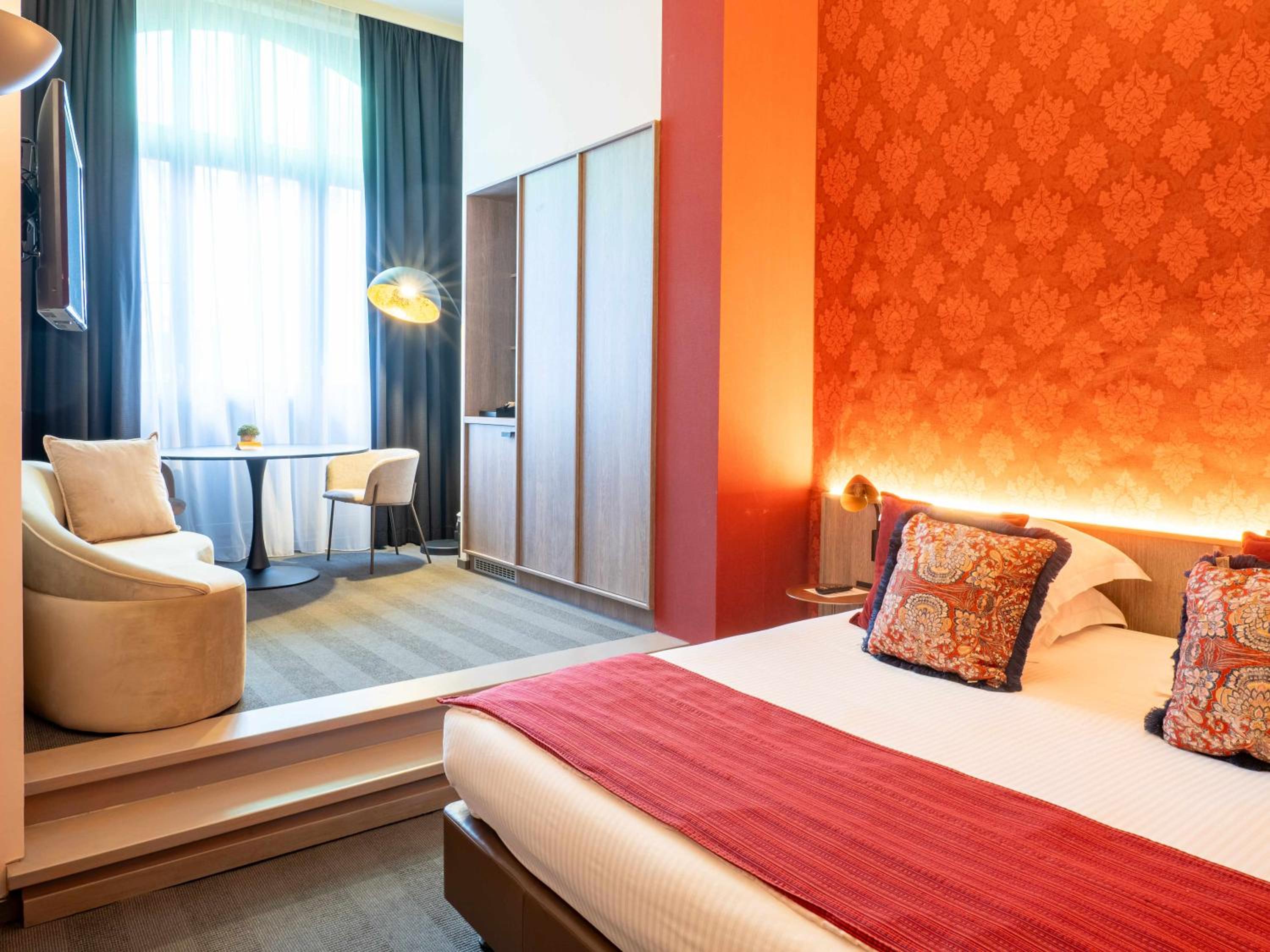 hotel room with an orange wall and a white bed