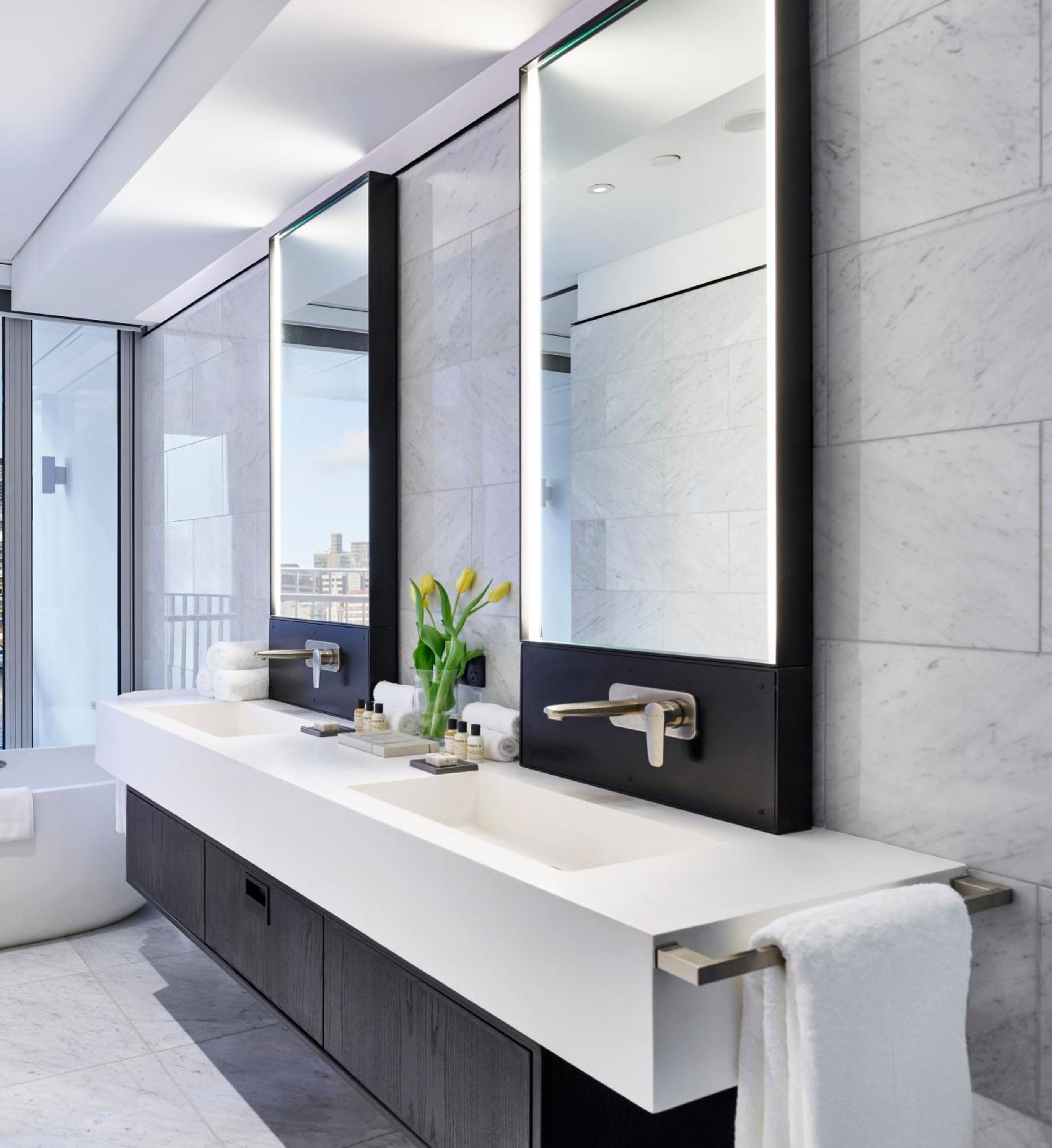 bathroom with two sinks, a tub and a large window