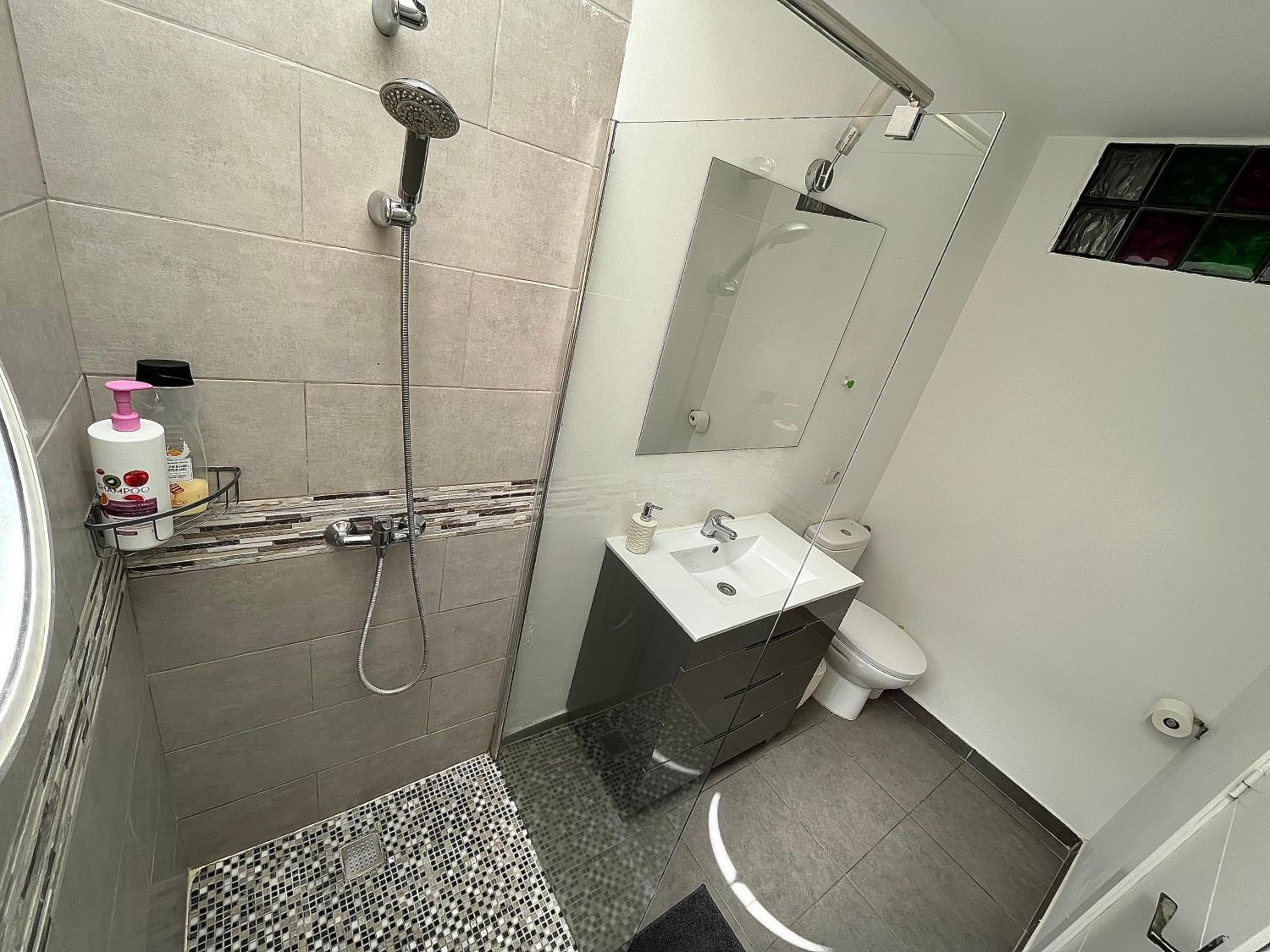 Small bathroom with walk-in tiled shower, vanity sink and toilet