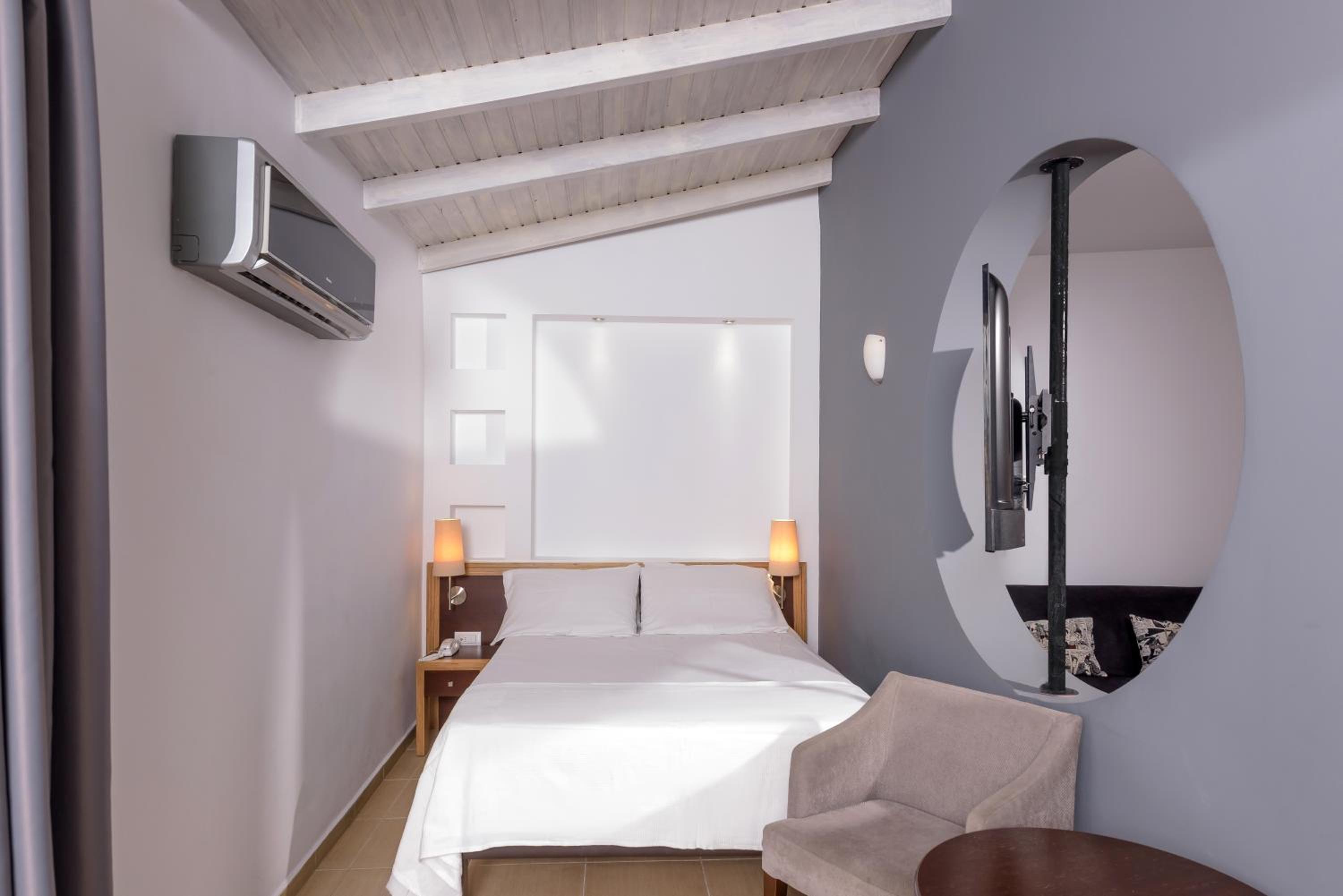 Hotel room with a white bed, wooden nightstands, and a circular wall opening.