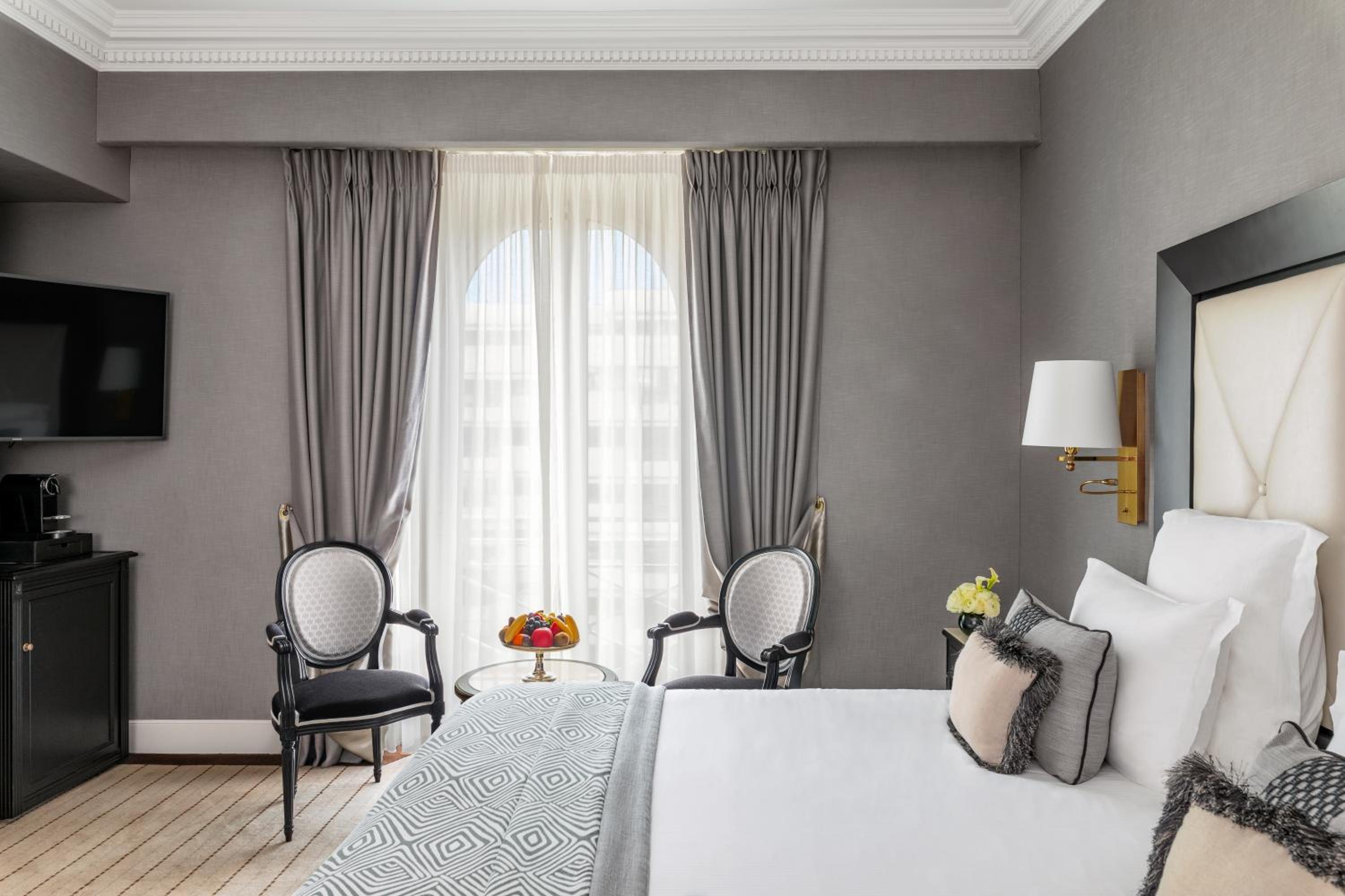 hotel room with a bed, two chairs, and a flat screen tv