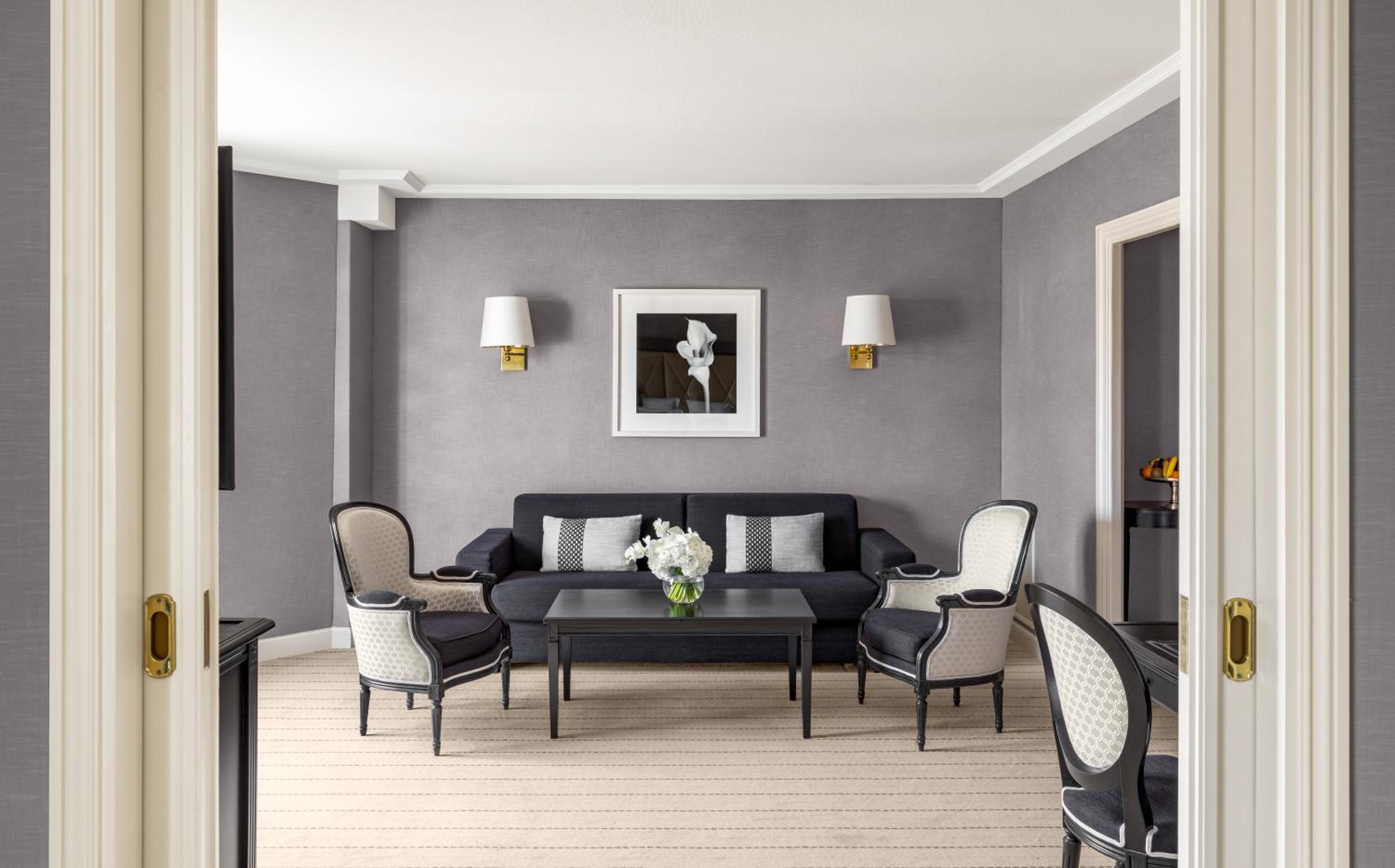 grey living room with a black couch and white chairs