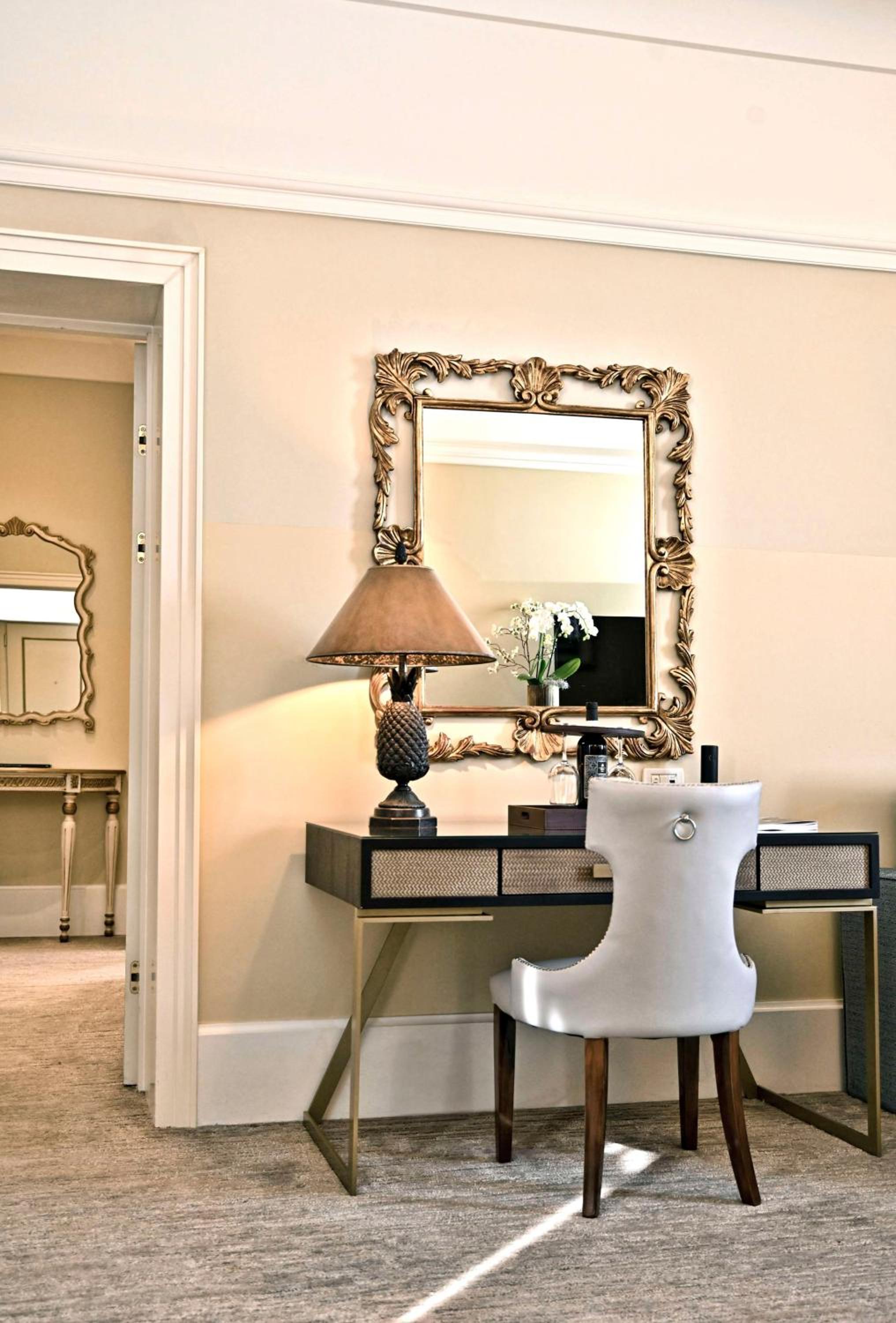room with a desk, chair, lamp and mirror