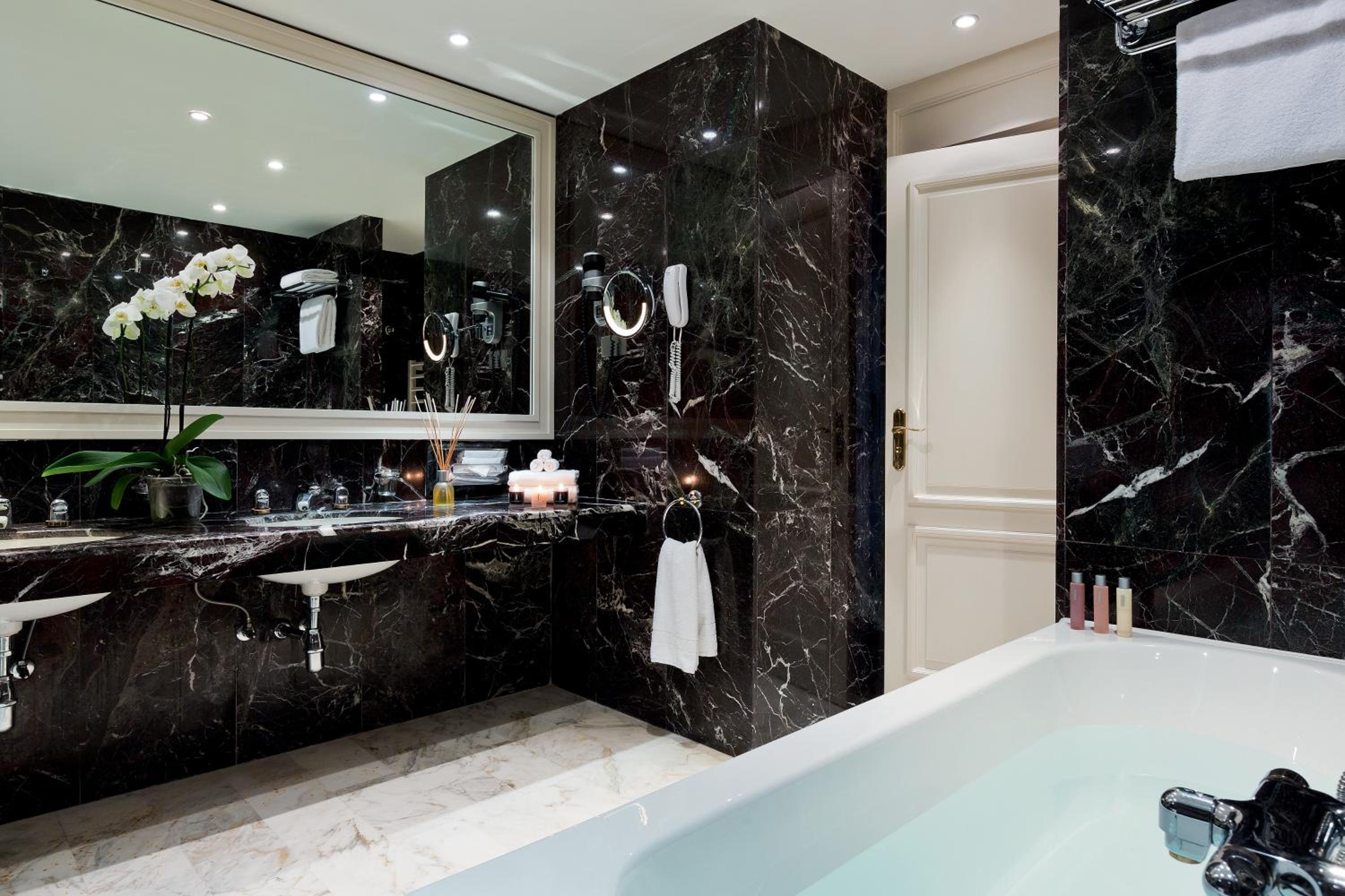 black marble bathroom with a bathtub and double sinks